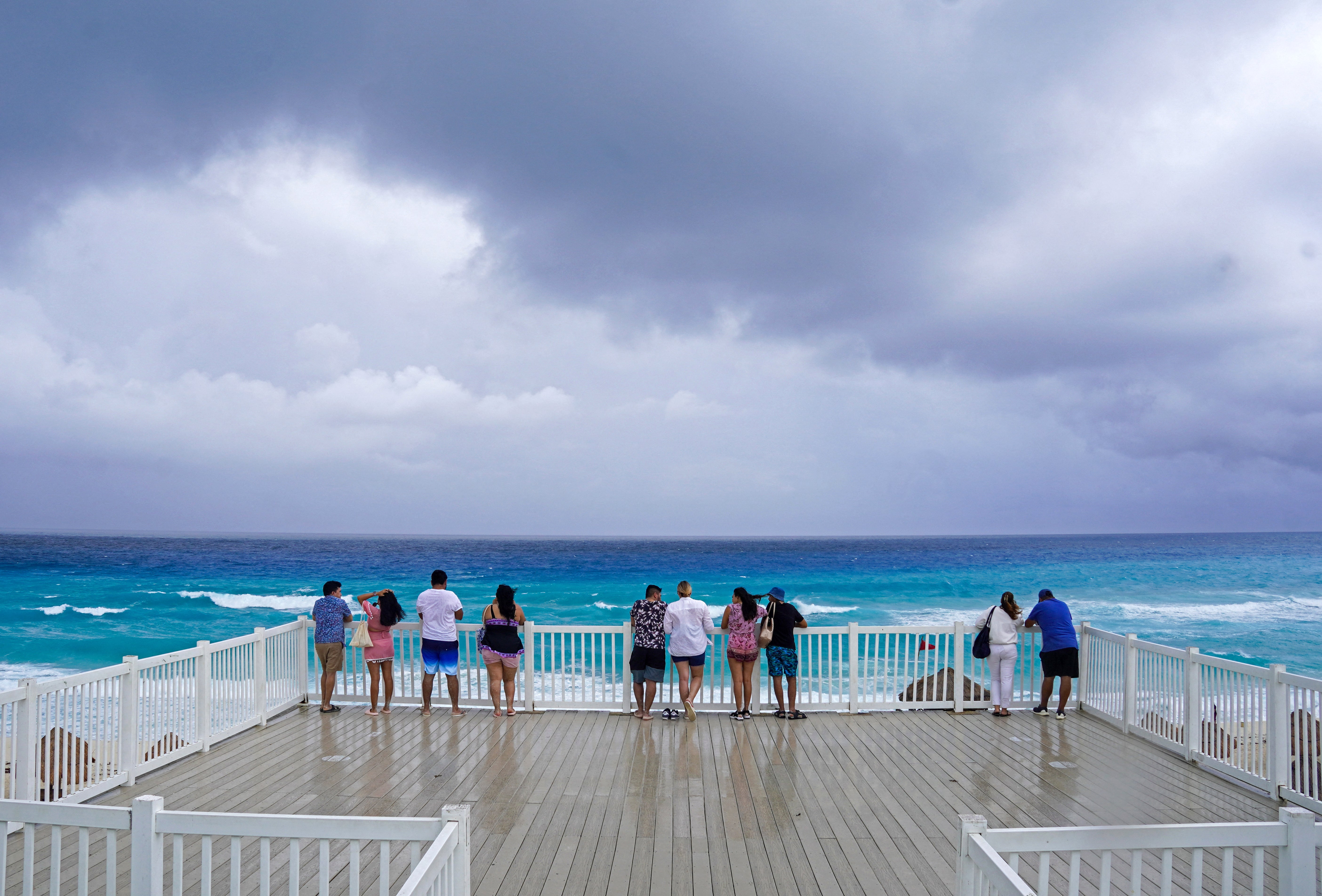 Beachgoers look out to sea on the beach ahead of the arrival of Tropical Storm Helene in Cancun on Tuesday