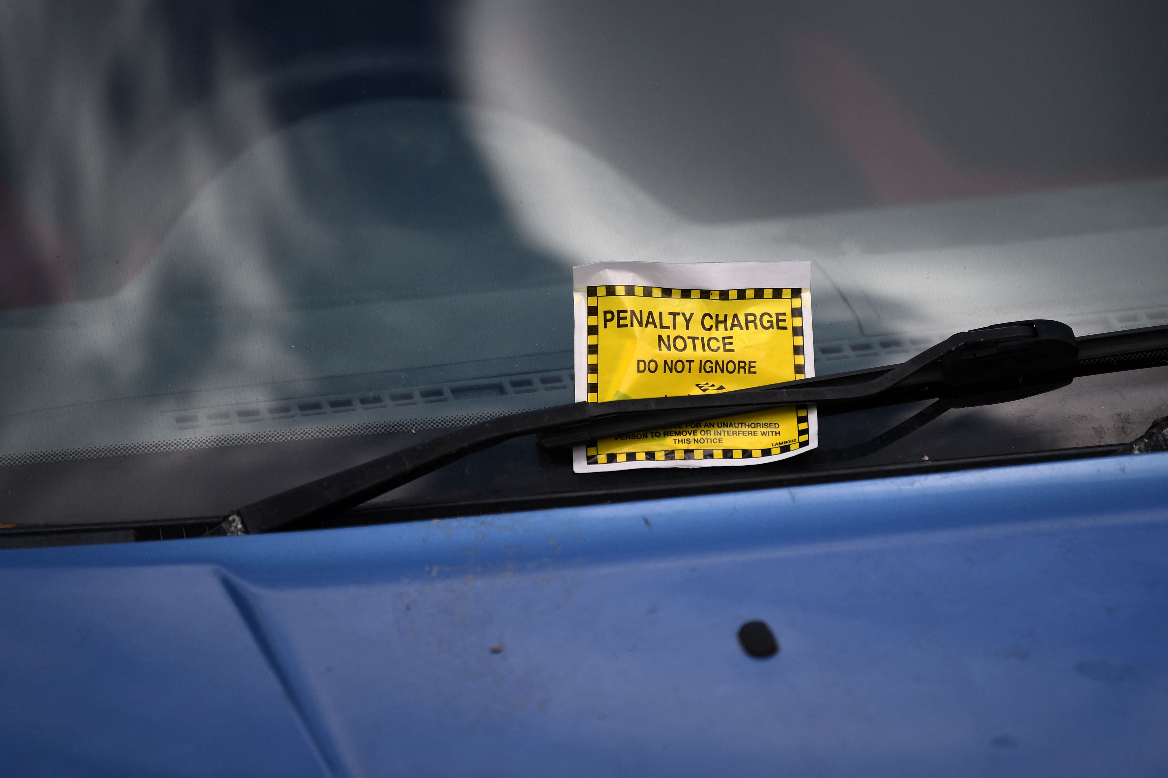 A Penalty Charge Notice (PCN) or parking ticket is pictured attached to the windscreen of a van in south London