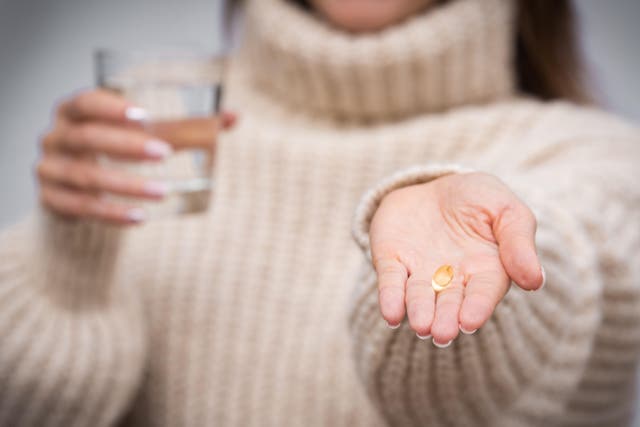 <p>A woman holding a Vitamin D tablet and a glass of water (Alamy/PA)</p>