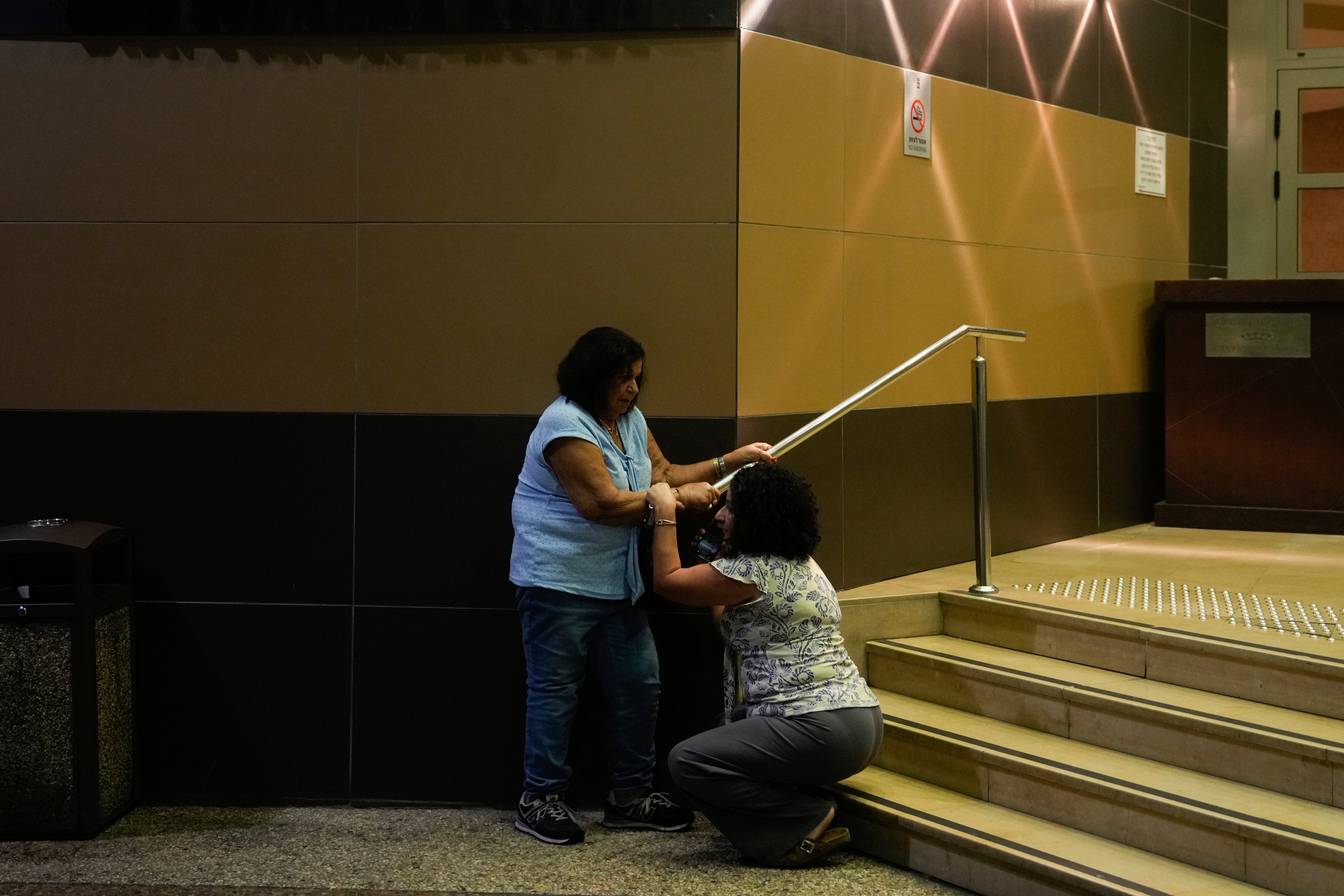 People take cover as a siren sounds a warning of incoming rockets fired from Lebanon, in Haifa