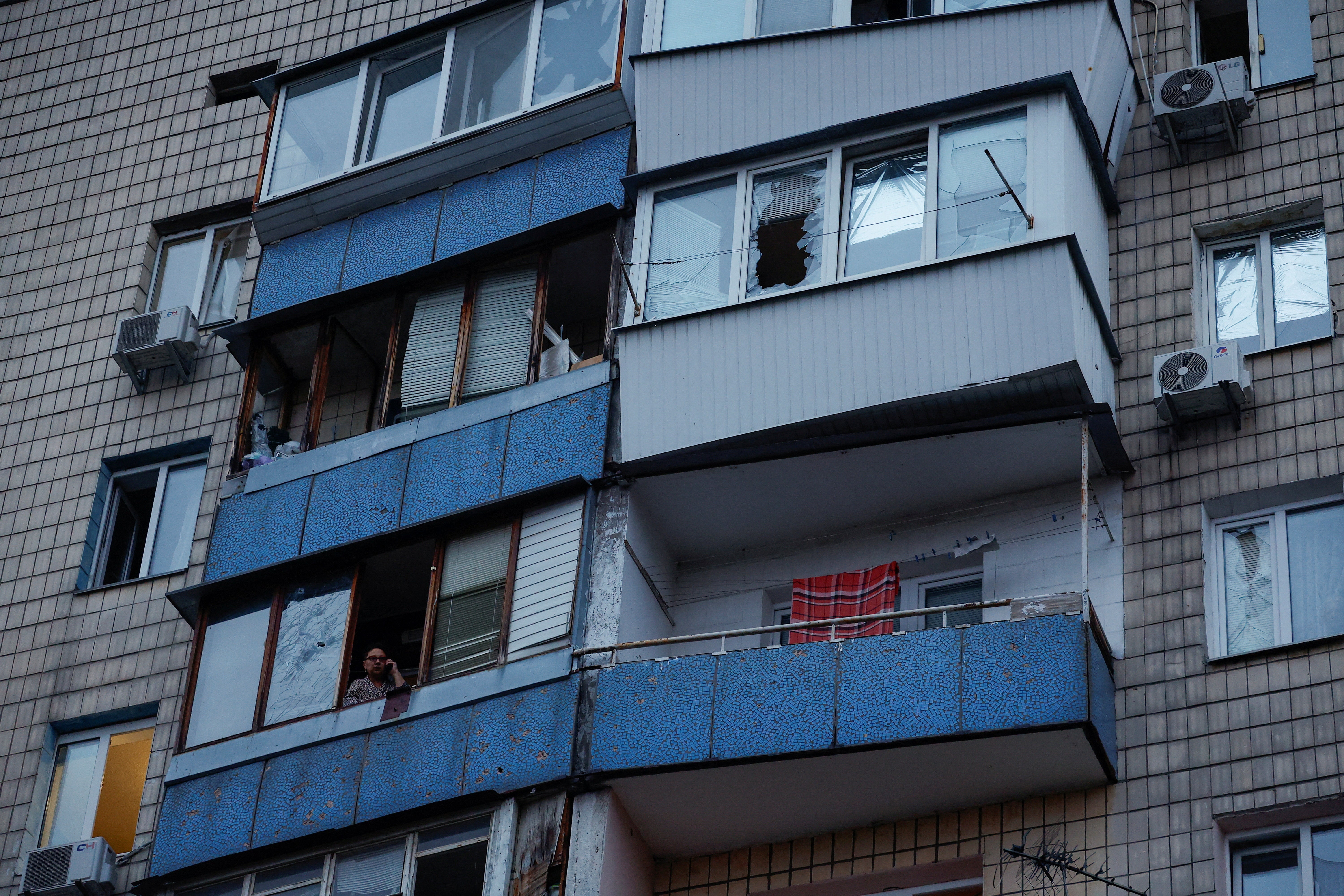 A woman speaks on her mobile phone in an apartment building damaged during a Russian drone strike, amid Russia's attack on Ukraine, in Kyiv, Ukraine