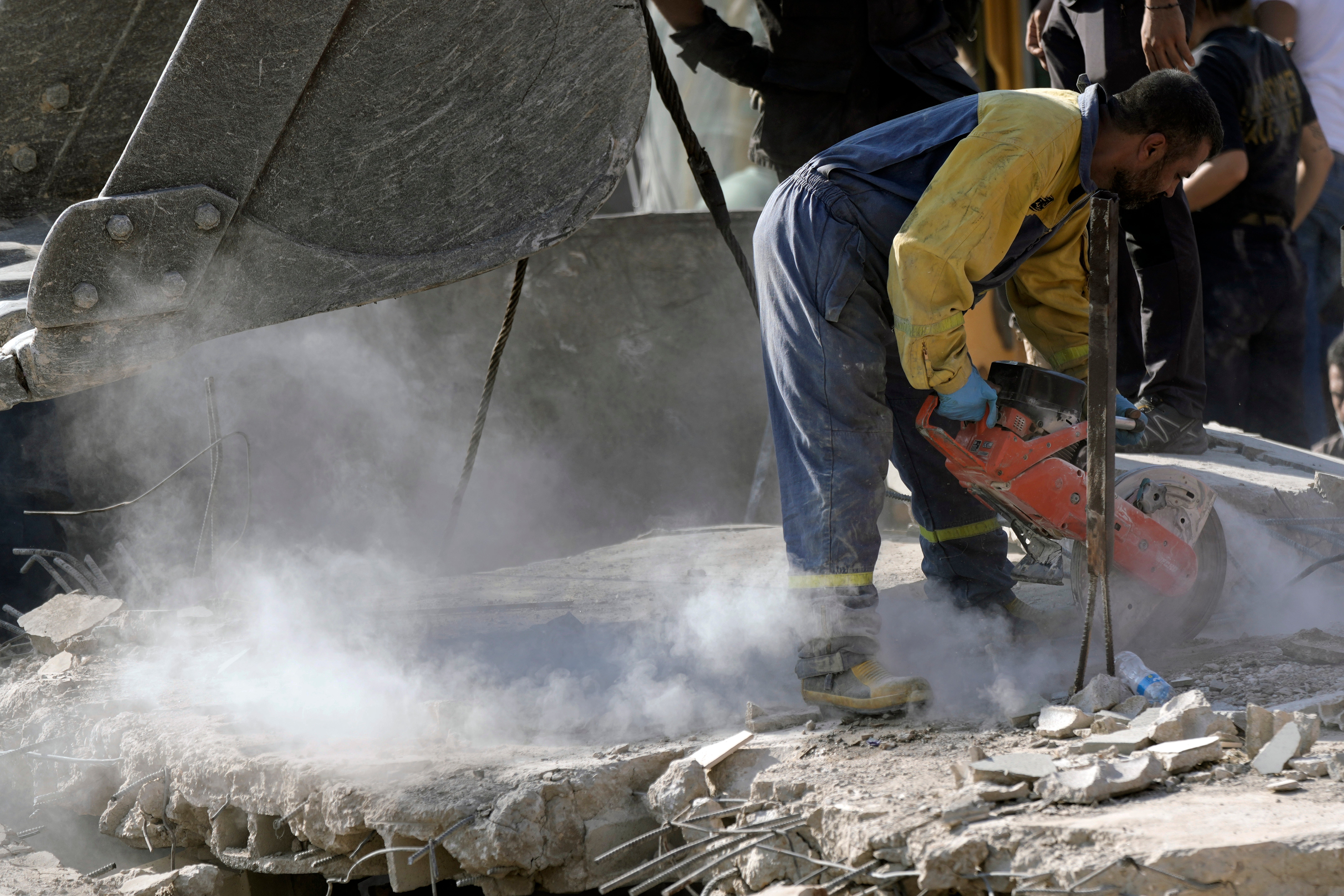 An emergency worker cuts through concrete blocks as he searches for survivors following an Israeli strike in Maisara, north of Beirut