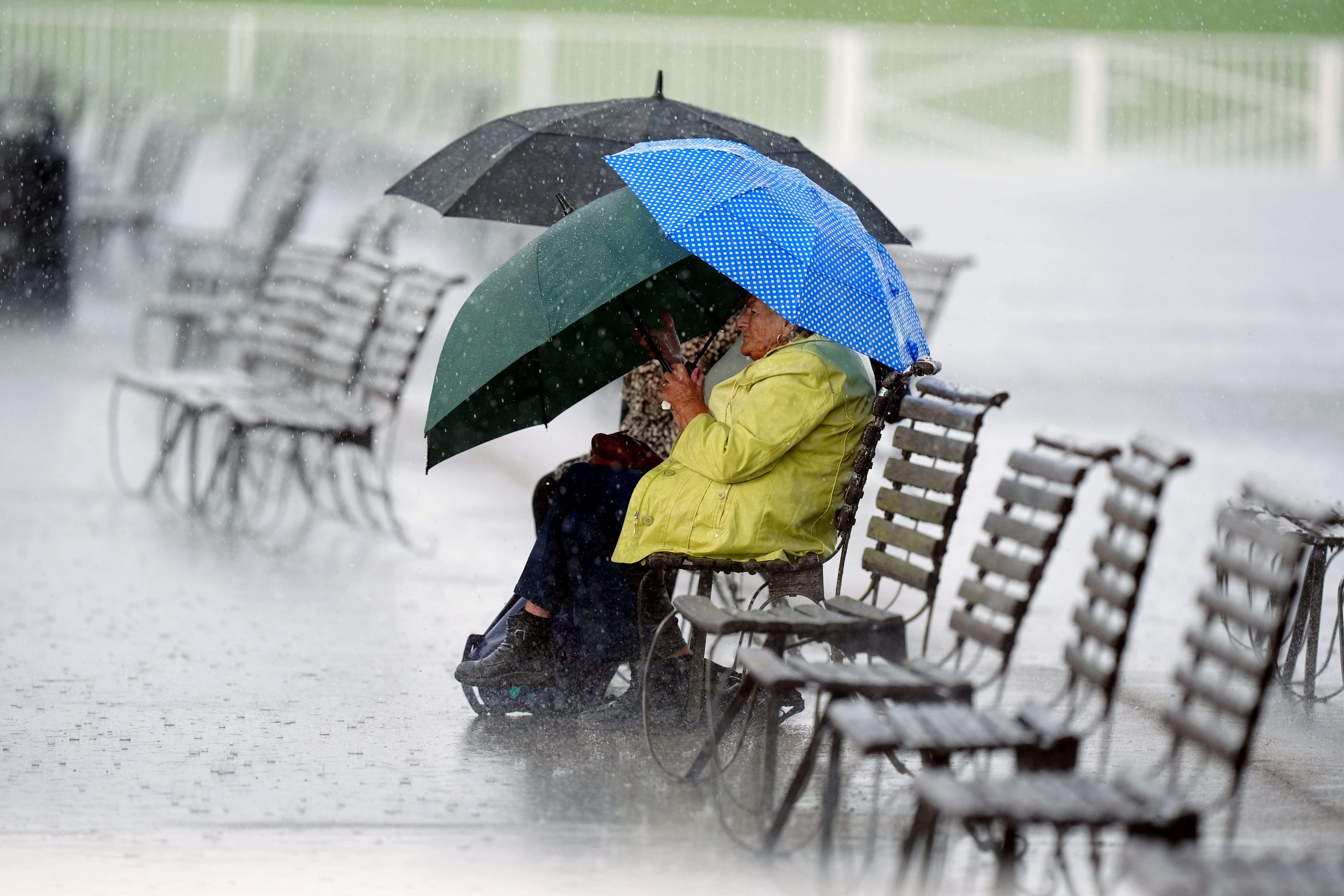 A racegoer shelters from the rain on day one of the Cambridgeshire Meeting at Newmarket Racecourse (Mike Egerton/PA)