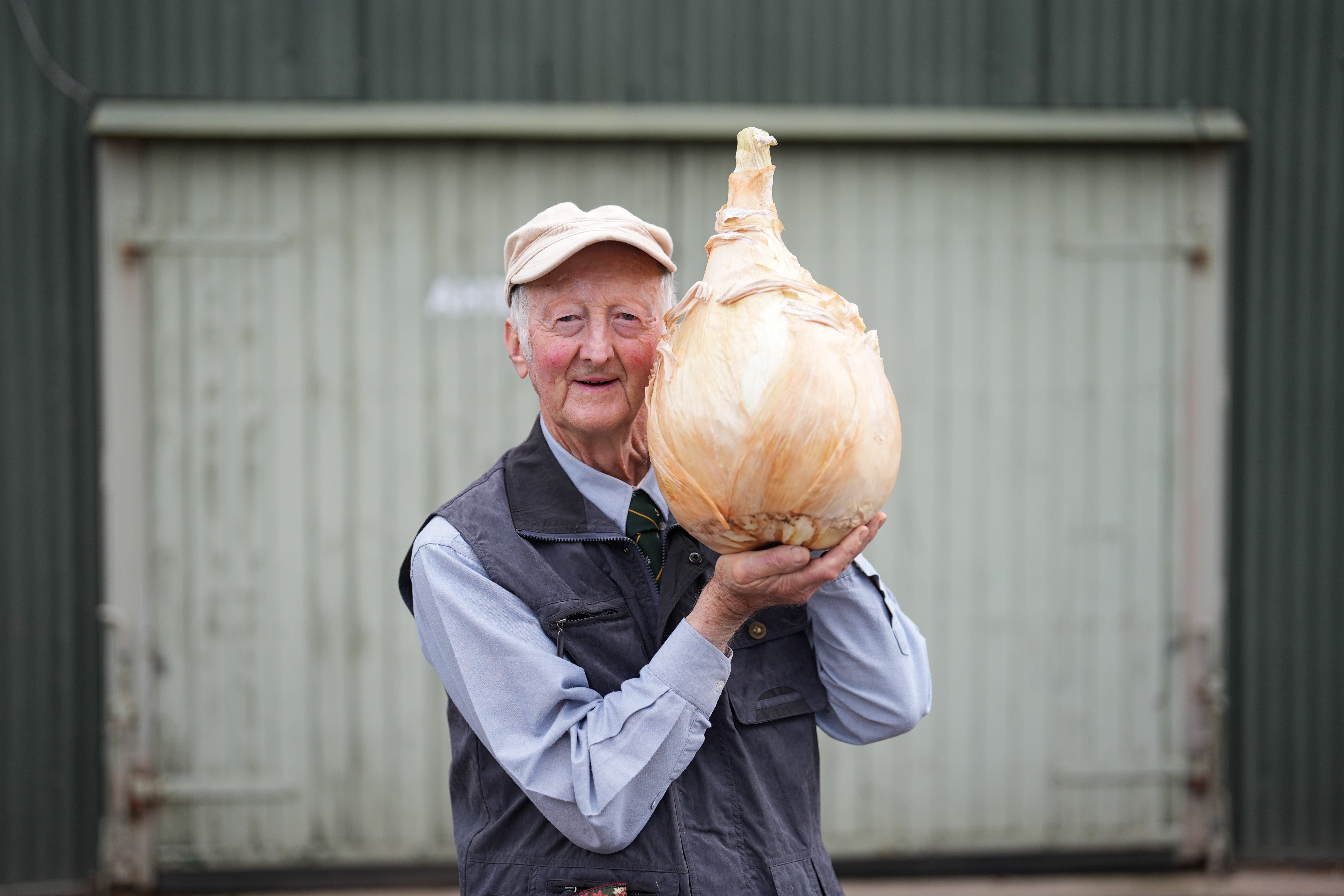 Peter Glazebrook holds a huge onion ahead of the UK national giant vegetables championship (Jacob King/PA)