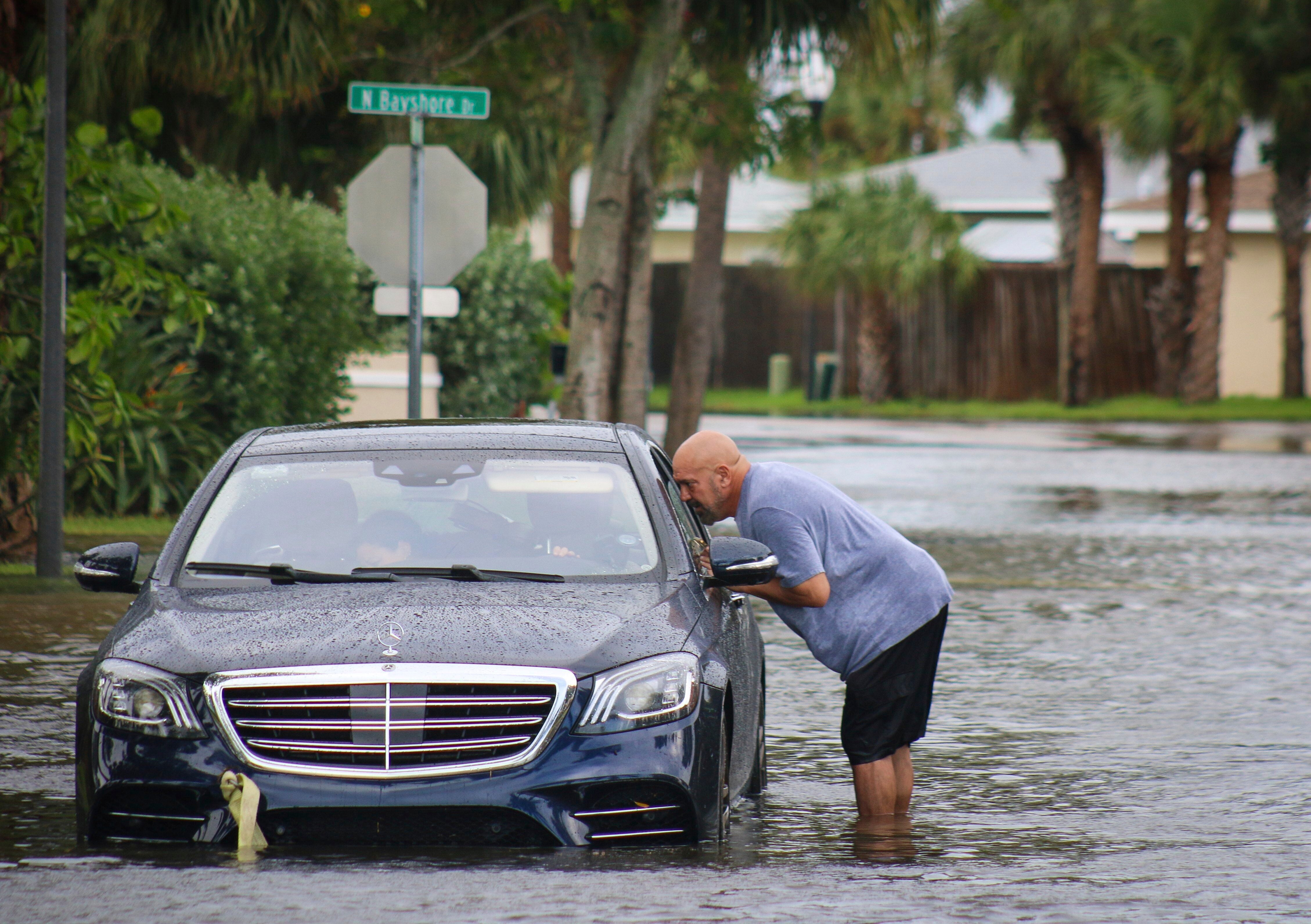 Melvin Juarbe attempts to assist an unidentified driver whose car stalled in floodwaters from Hurricane Helene on Thursday.