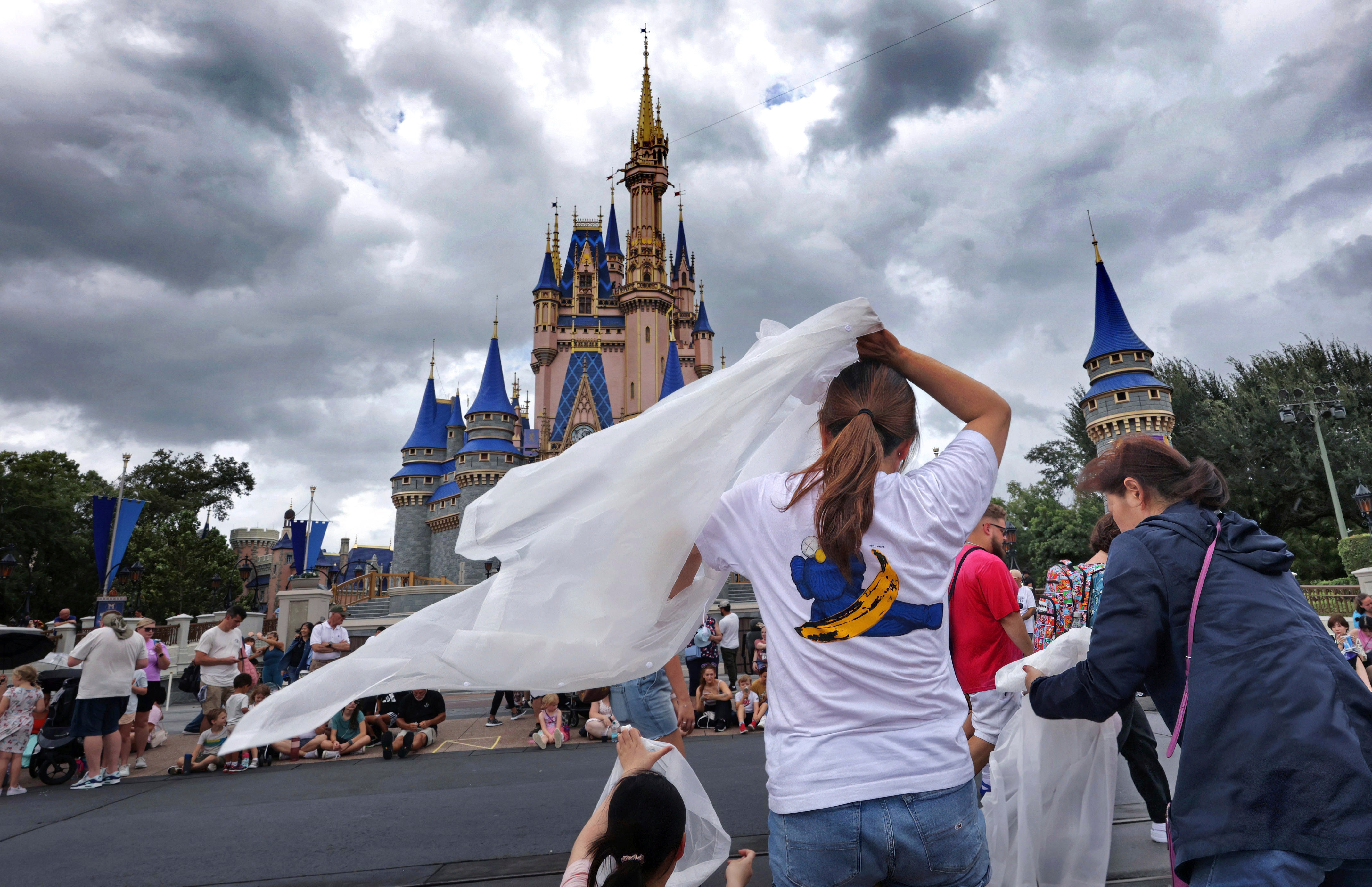 Guests at the Magic Kingdom break out ponchos at Cinderella Castle as bands of weather from Hurricane Helene