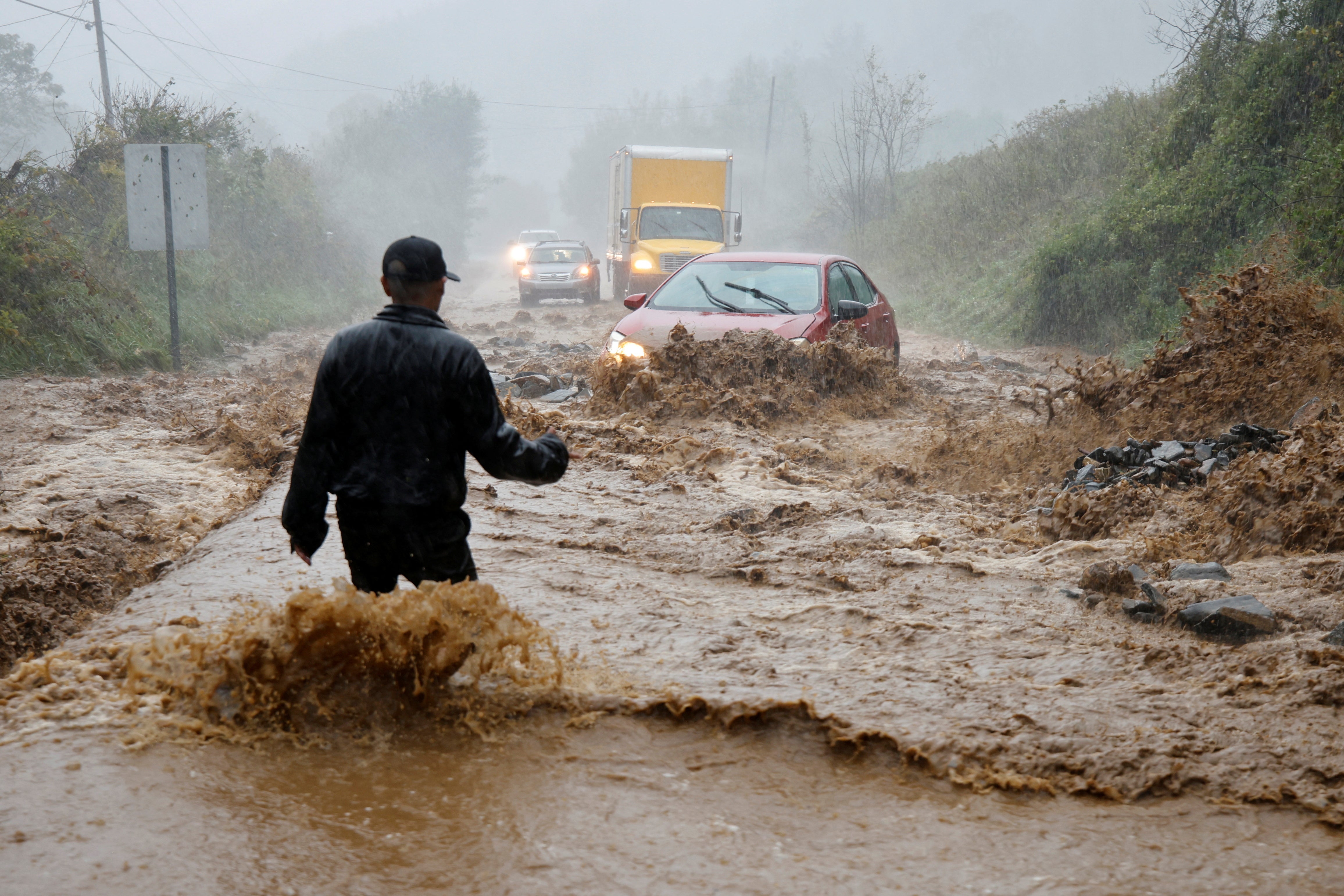 A local resident walks out into fast-flowing waters to assist a stranded driver on Friday in Boone, North Carolina