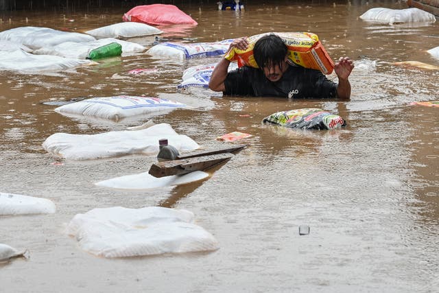 <p>A man carrying a sack of flour wades through flood waters after the Bagmati River overflowed following heavy monsoon rains in Kathmandu </p>