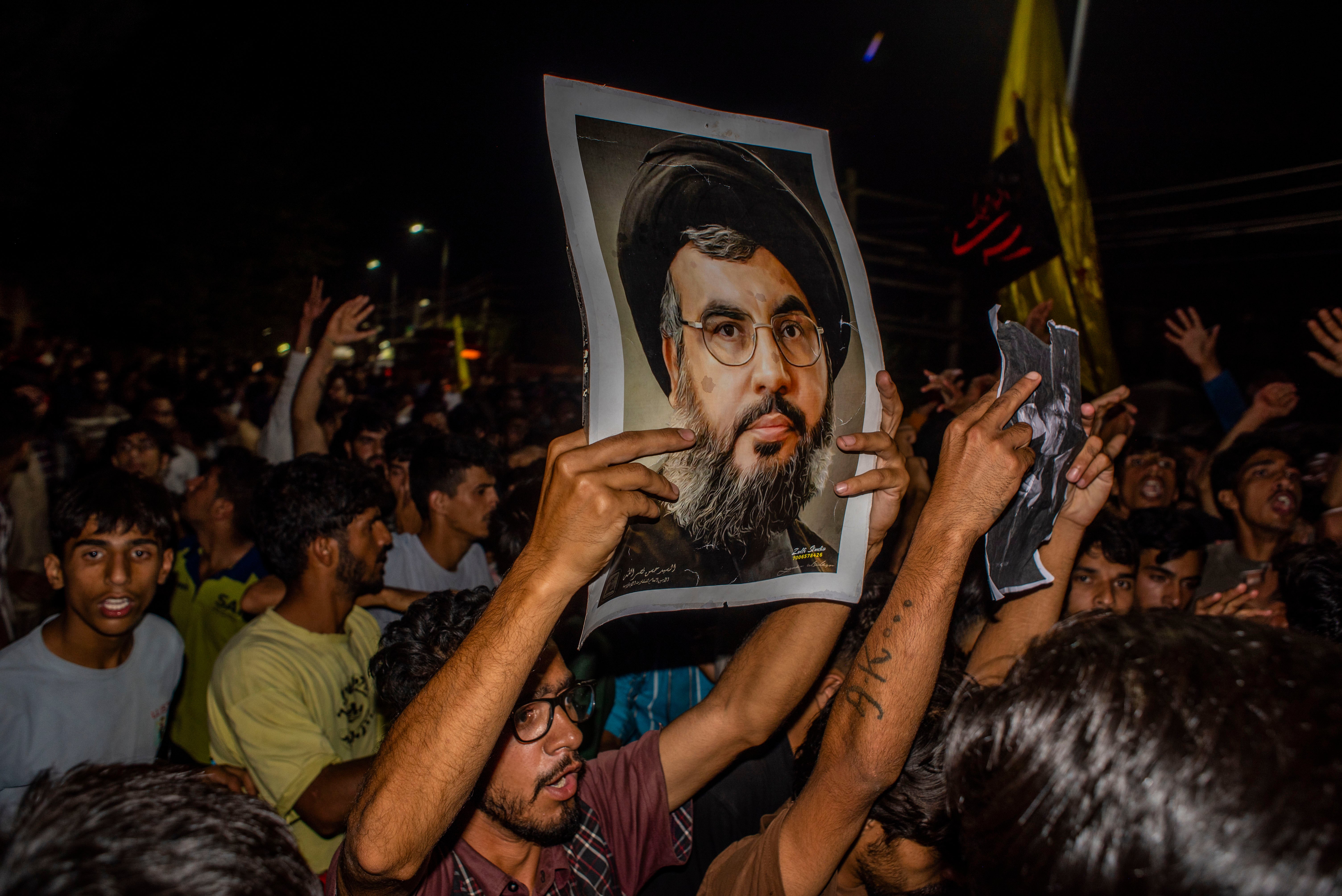 Kashmiri Shiite Muslims holding the picture of Hassan Nasrallah as they try to march, chanting anti-Israel and anti-US slogans