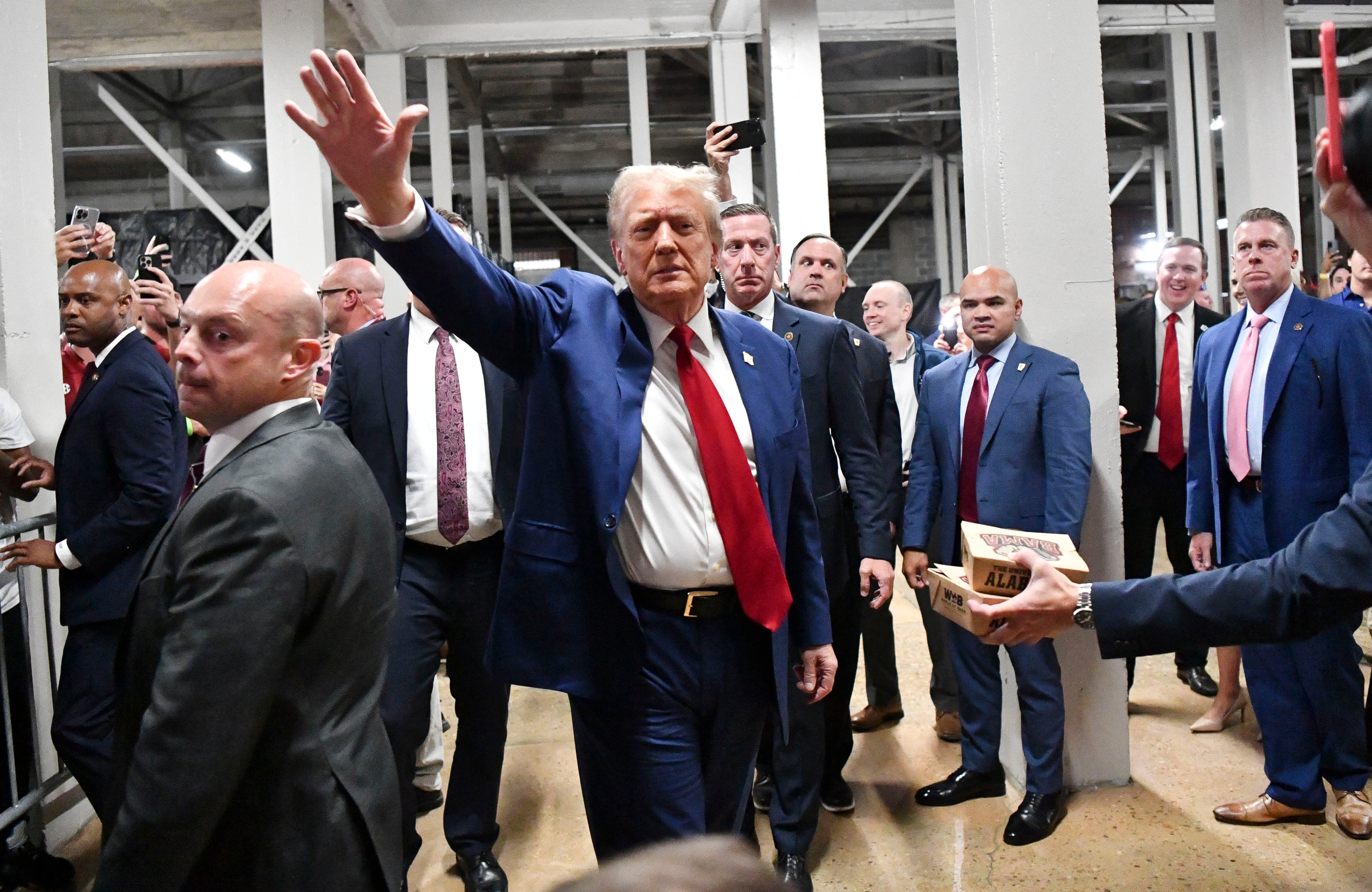 Donald Trump waves to onlookers as her attends the game between Alabama and Georgia at the Bryant-Denny Stadium