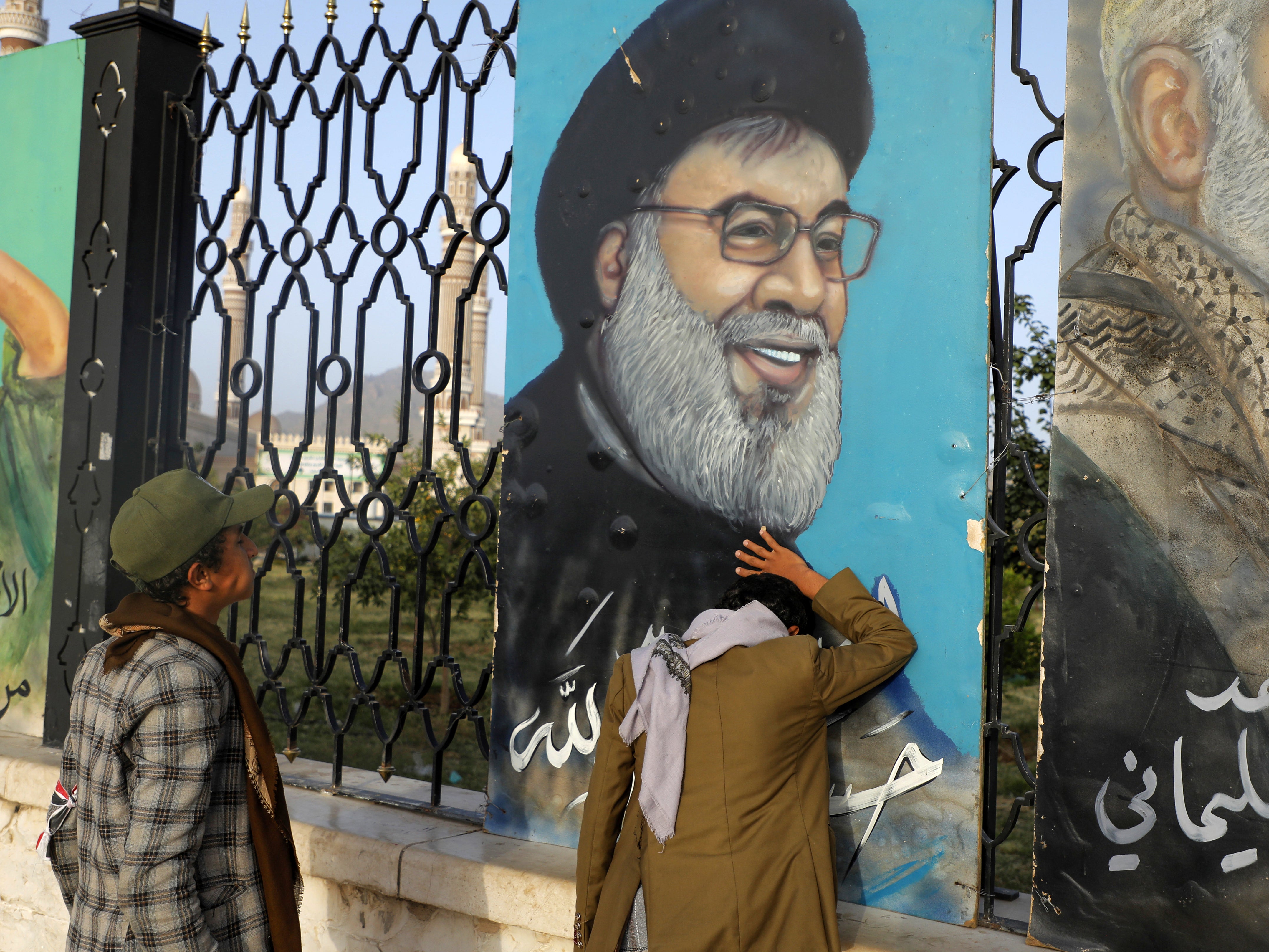 Yemenis stand in front of a portrait of Hezbollah leader Sayyed Hassan Nasrallah, in Sanaa, Yemen