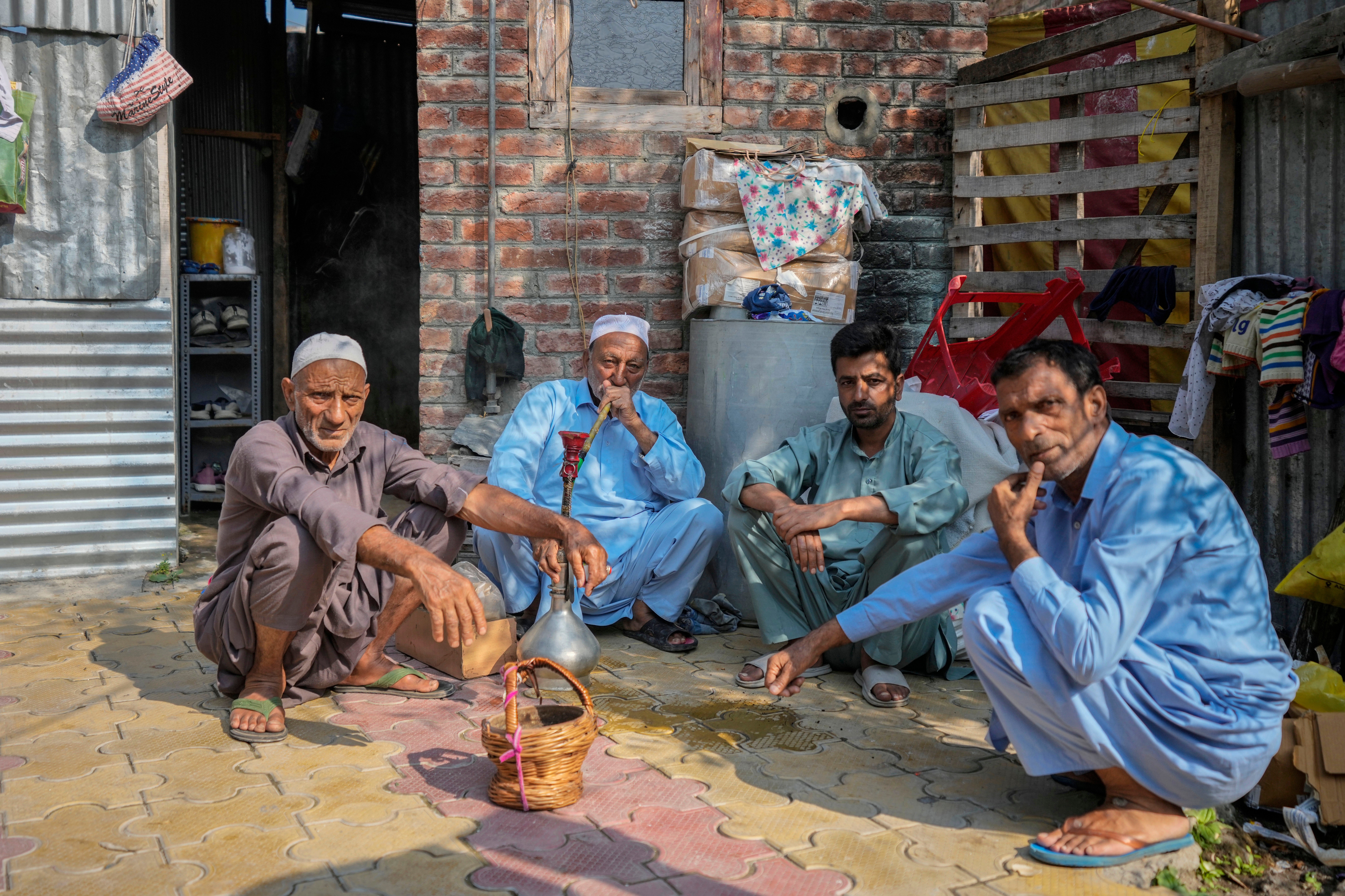 An elderly man smokes a hookah pipe as he sits with other men outside a polling station during the second phase of the assembly election in the interior of Dal Lake in Srinagar, Indian controlled Kashmir, 25 Sept 2024