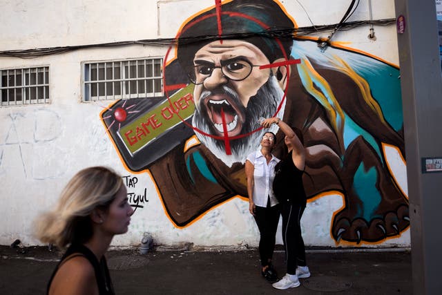 <p>Two women take a selfie next to a newly painted graffiti of Hezbollah leader Hassan Nasrallah, a day after Hezbollah confirms its leader was killed in an Israeli airstrike, in Tel Aviv, Israel, on Sunday, Sept. 29</p>