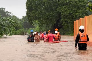 Rescuers help residents as they negotiate floods caused by powerful Typhoon Krathon