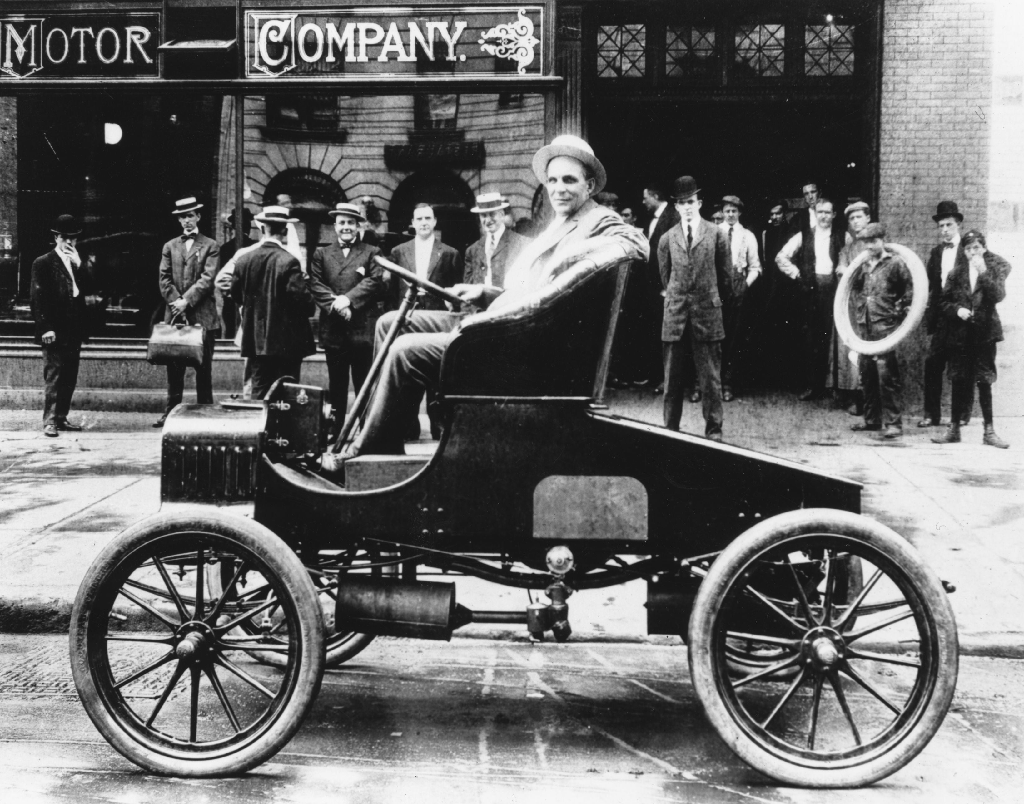 Henry Ford posa com um de seus veículos