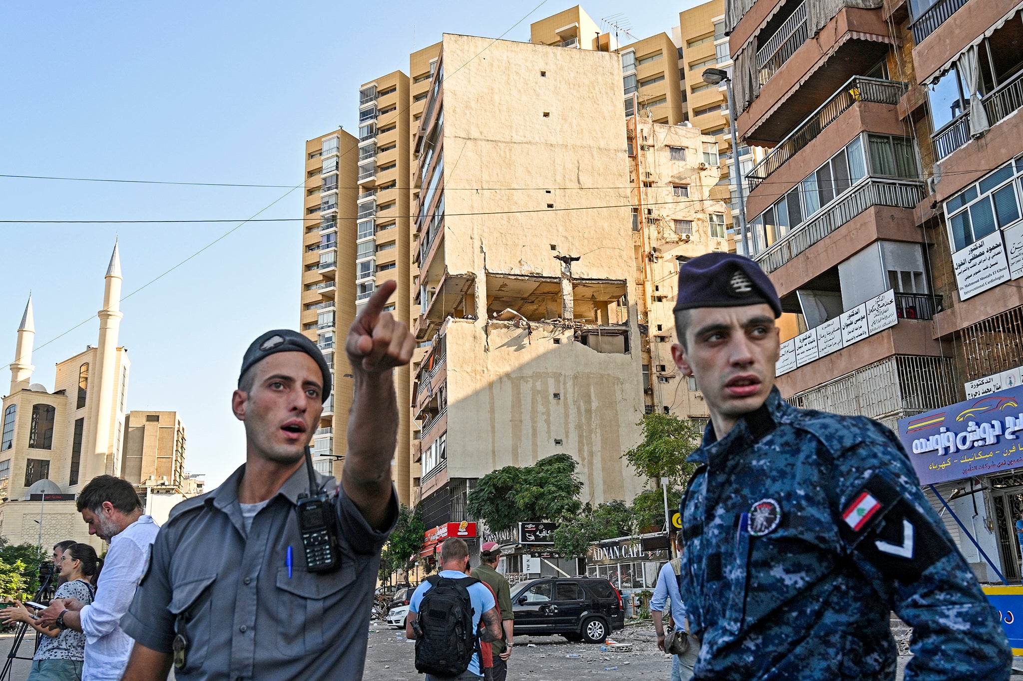 Lebanese policemen secure the area around a damaged building following overnight Israeli strikes in the Cola area of Beirut