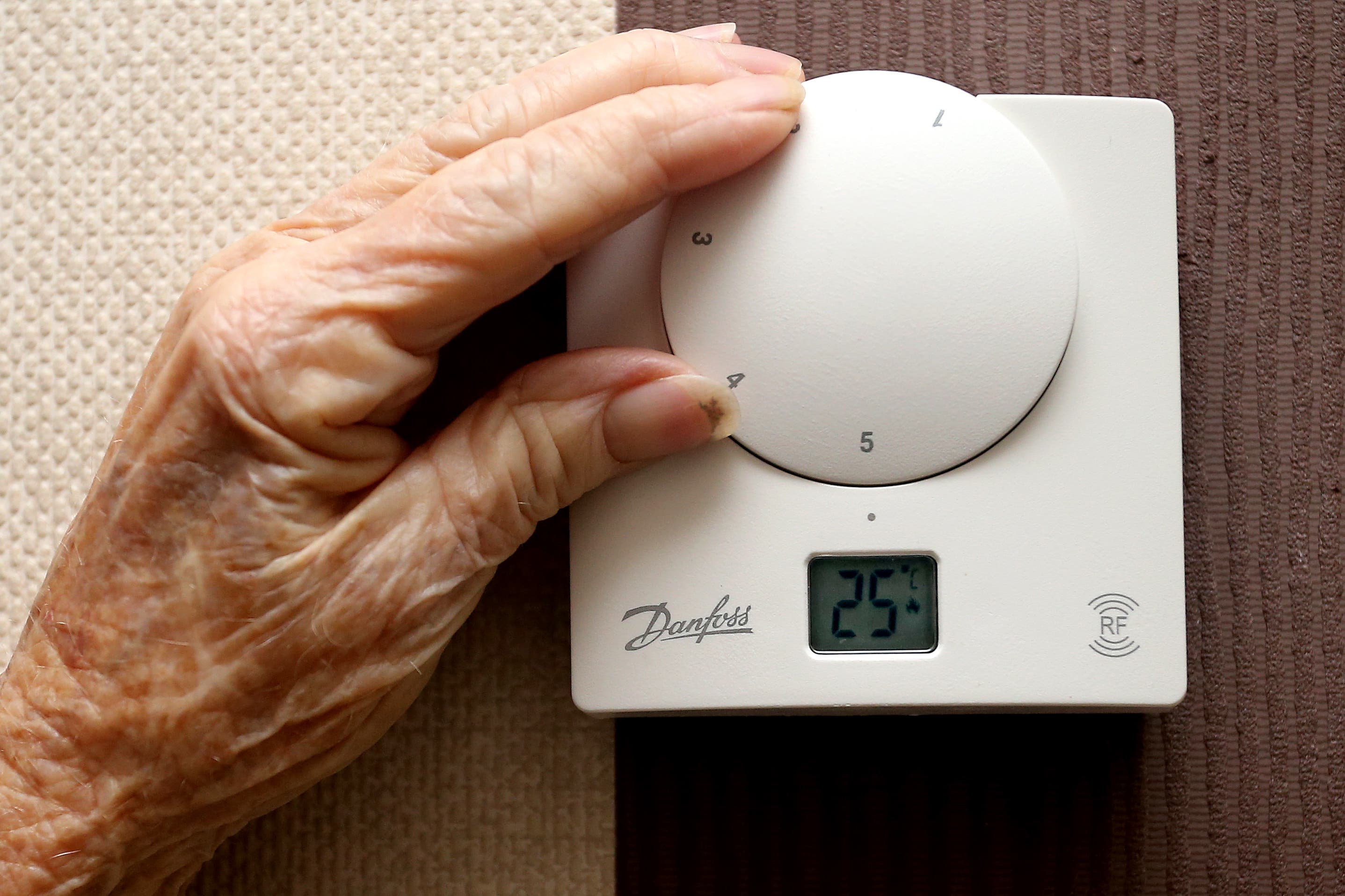 An elderly woman adjusts her thermostat at home in Liverpool (PA)