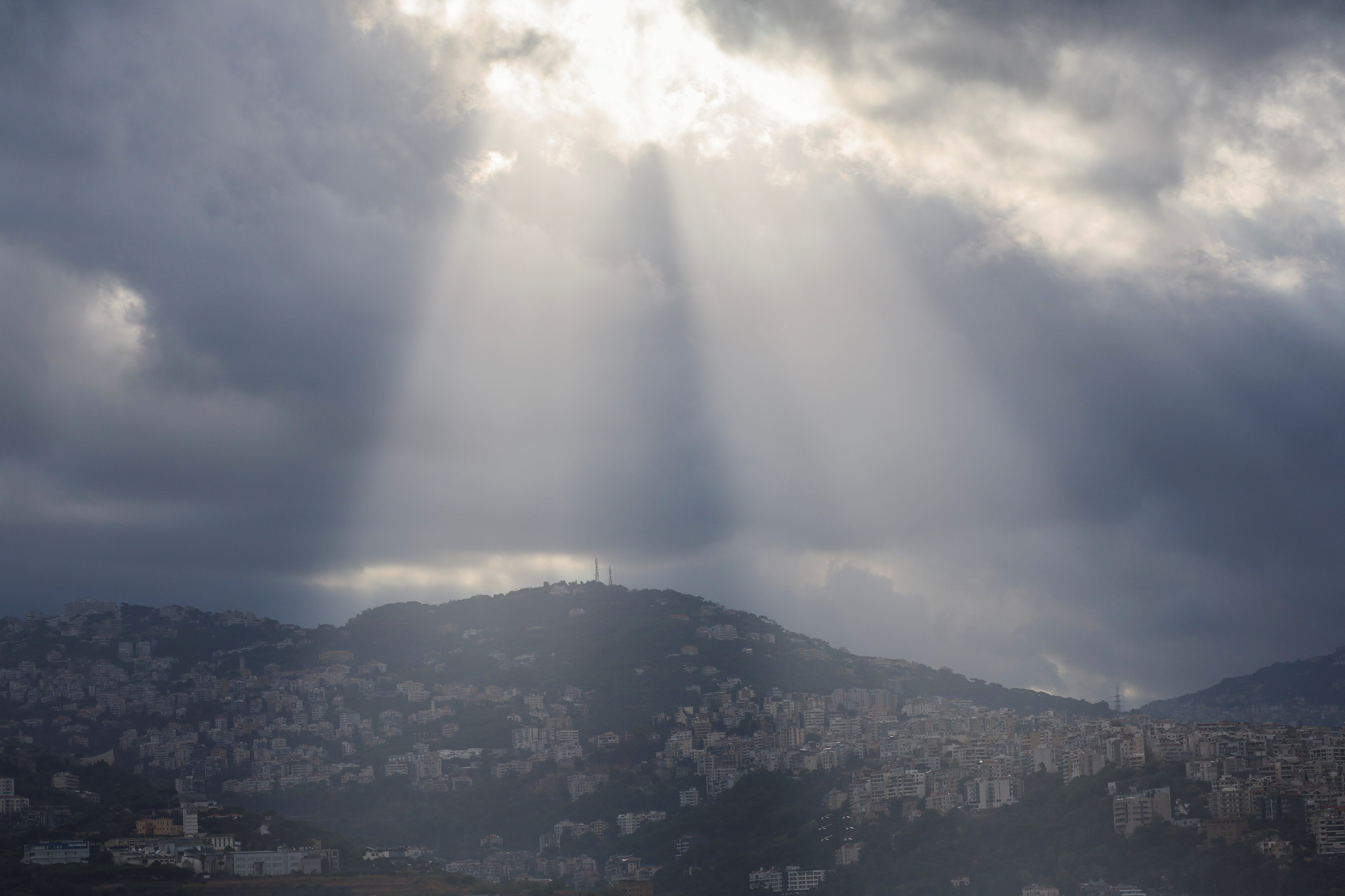 Sunlight illuminates through the clouds over the mountains and Beirut's southern suburbs following heavy rainfall, amid the ongoing hostilities between Hezbollah and Israeli forces, in Beirut, Lebanon