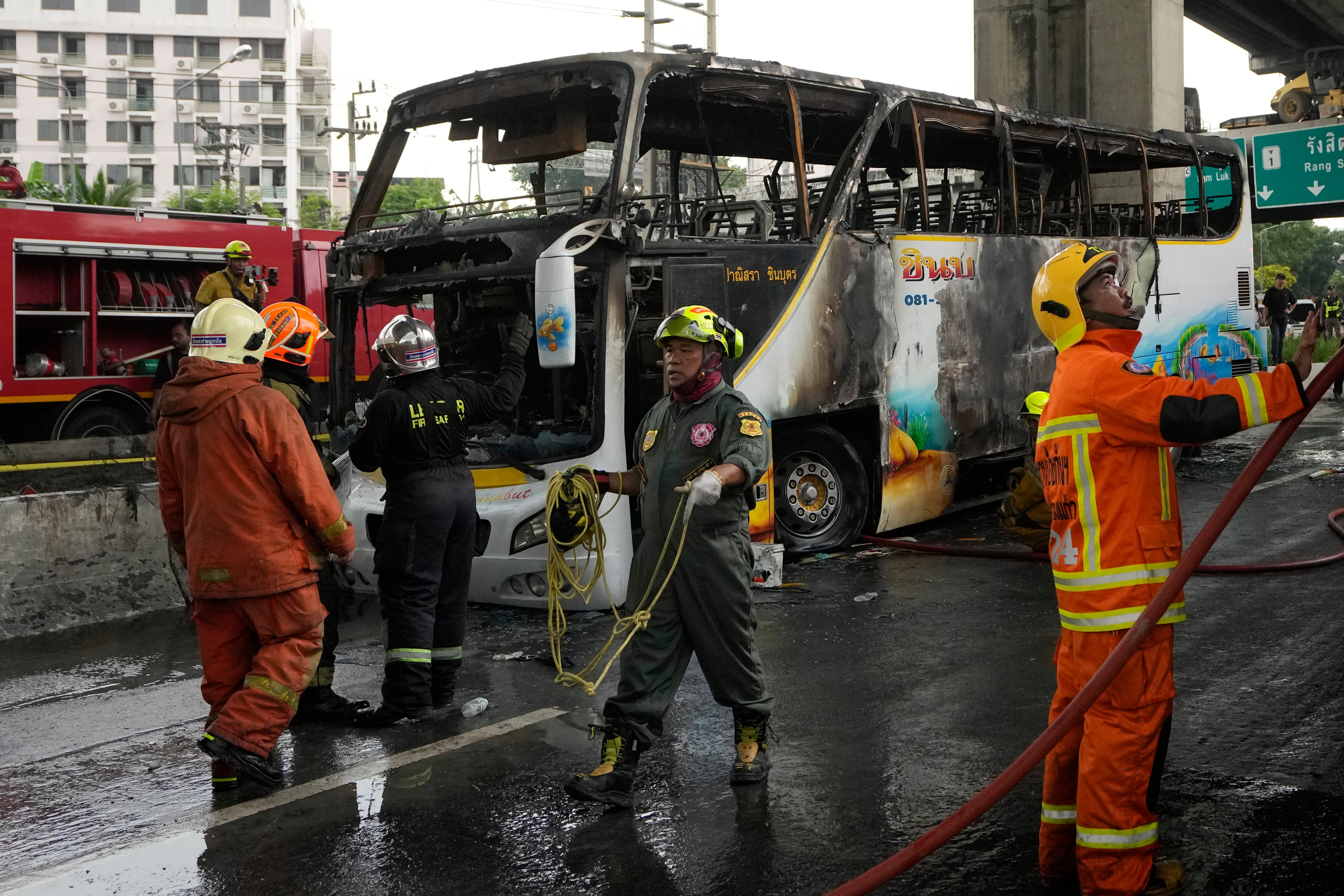 Rescuers work at the site of a bus that caught fire, carrying young students with their teachers, in suburban Bangkok