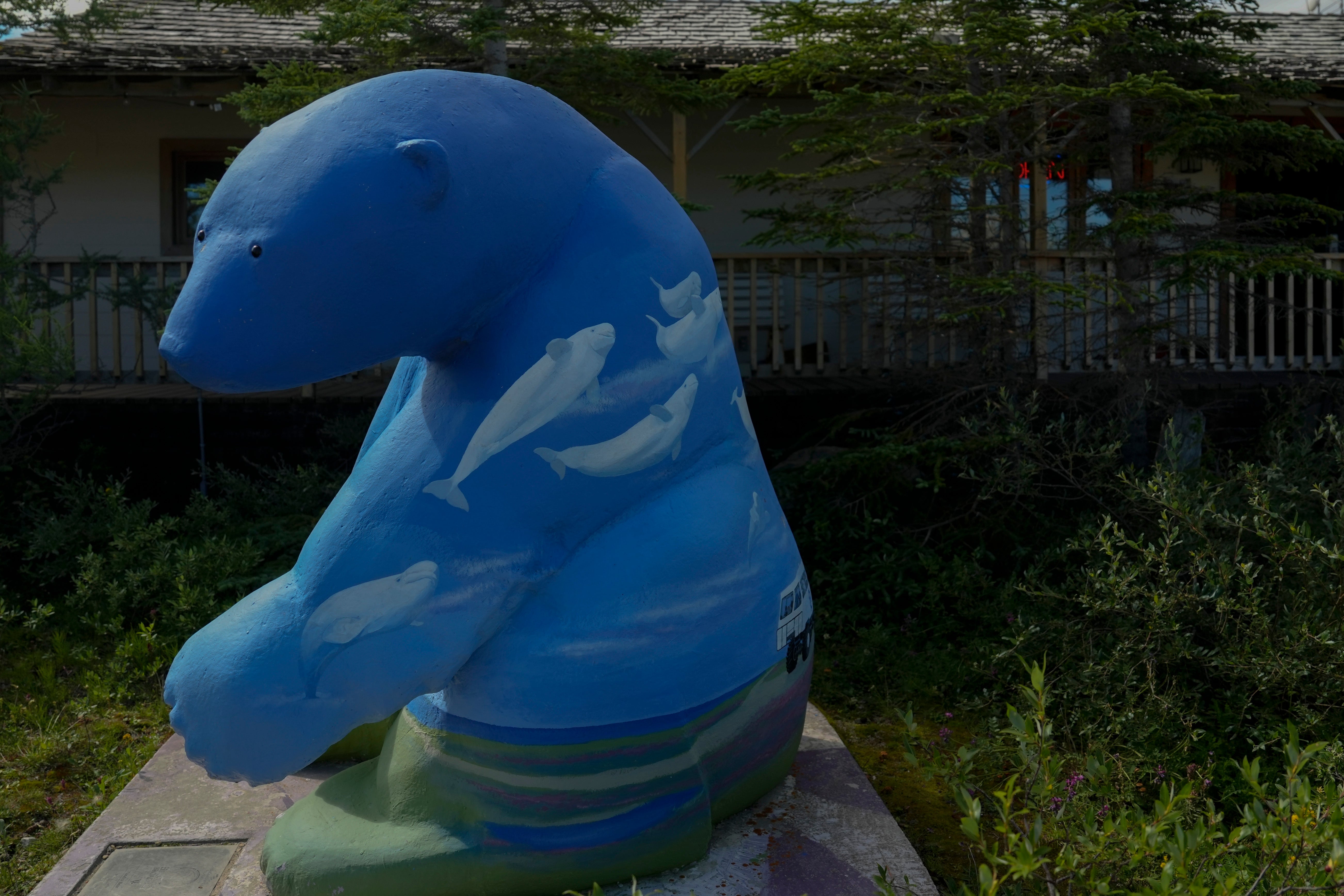 A polar bear statue with painted beluga whales sits outside a gift shop, Tuesday, Aug. 6, 2024, in Churchill