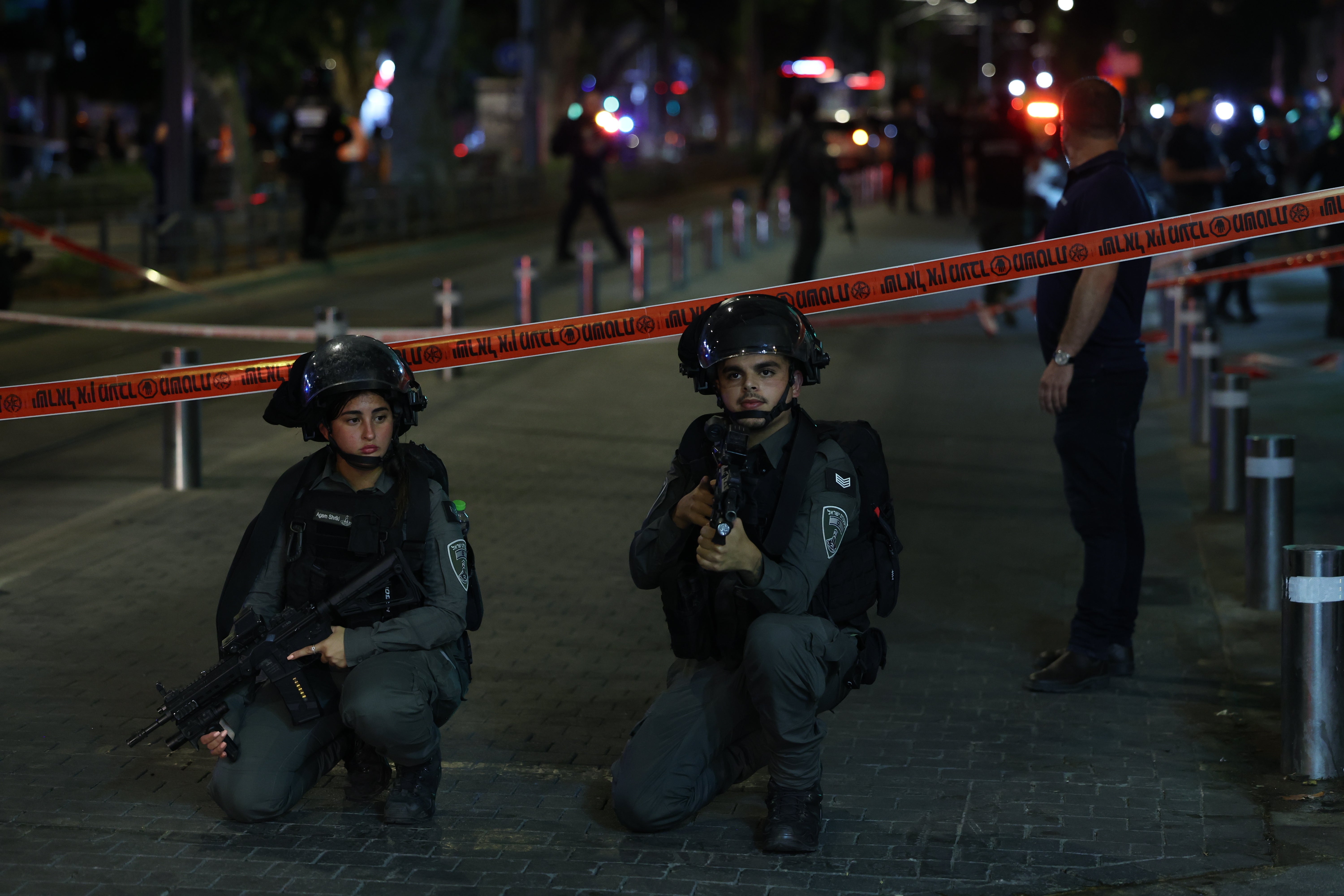 Armed Israeli police officers keep watch near a cordon at the site of a shooting incident in Tel Aviv on Tuesday