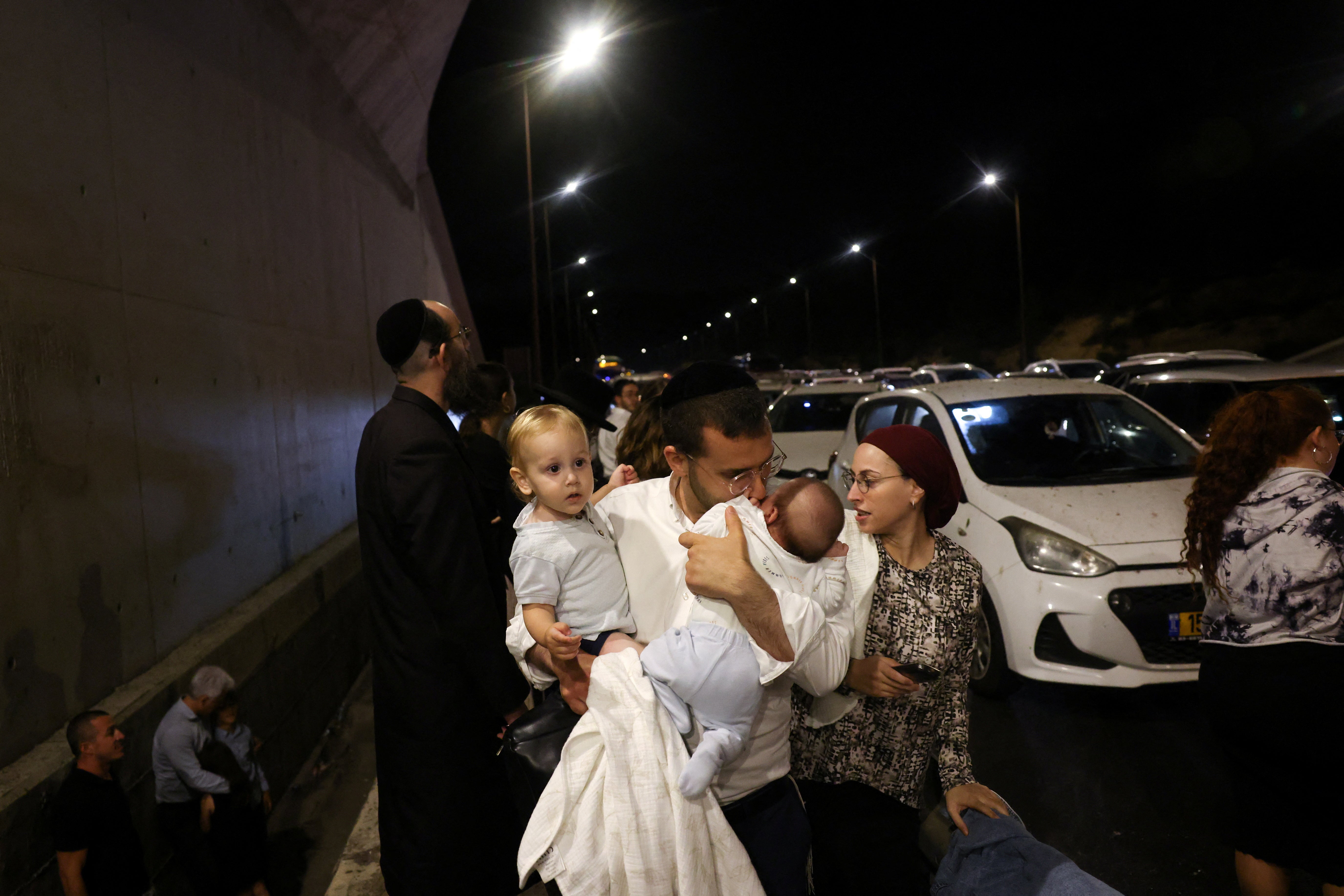 A man holds children as people take cover during an air raid siren