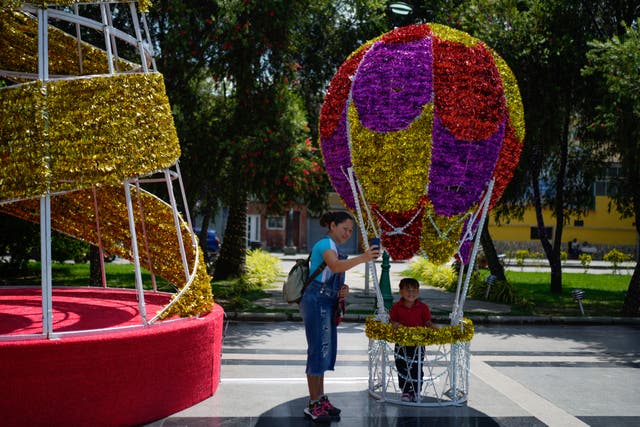 <p>A woman takes a selfie with her daughter inside a Christmas decoration in Caracas, Venezuela, Tuesday, October 1</p>