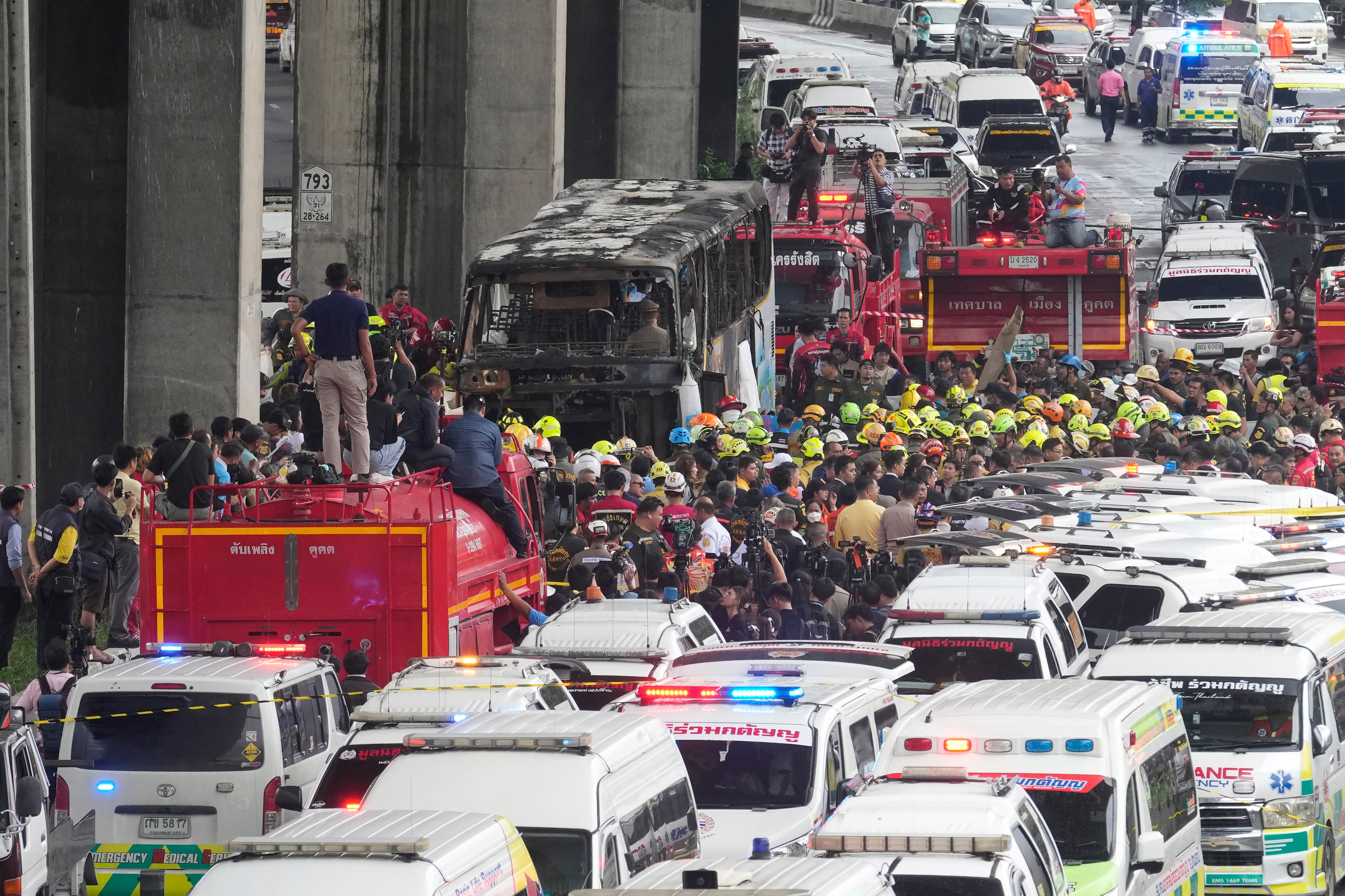 Rescuers gather at the site of a bus that caught fire, carrying young students with their teachers