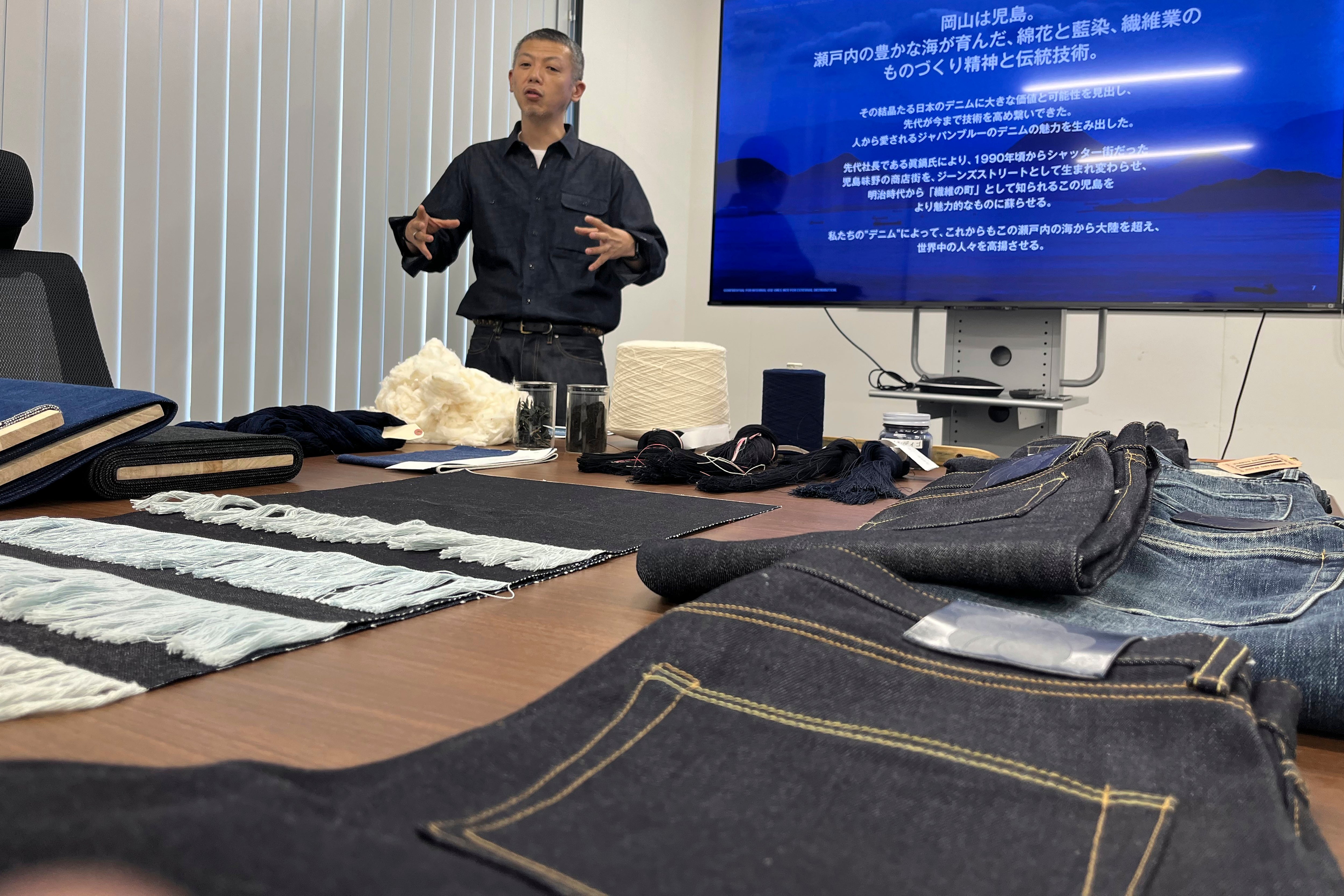 Japan Blue Co. President and Chief Operating Officer Masataka Suzuki shows some of the jeans products