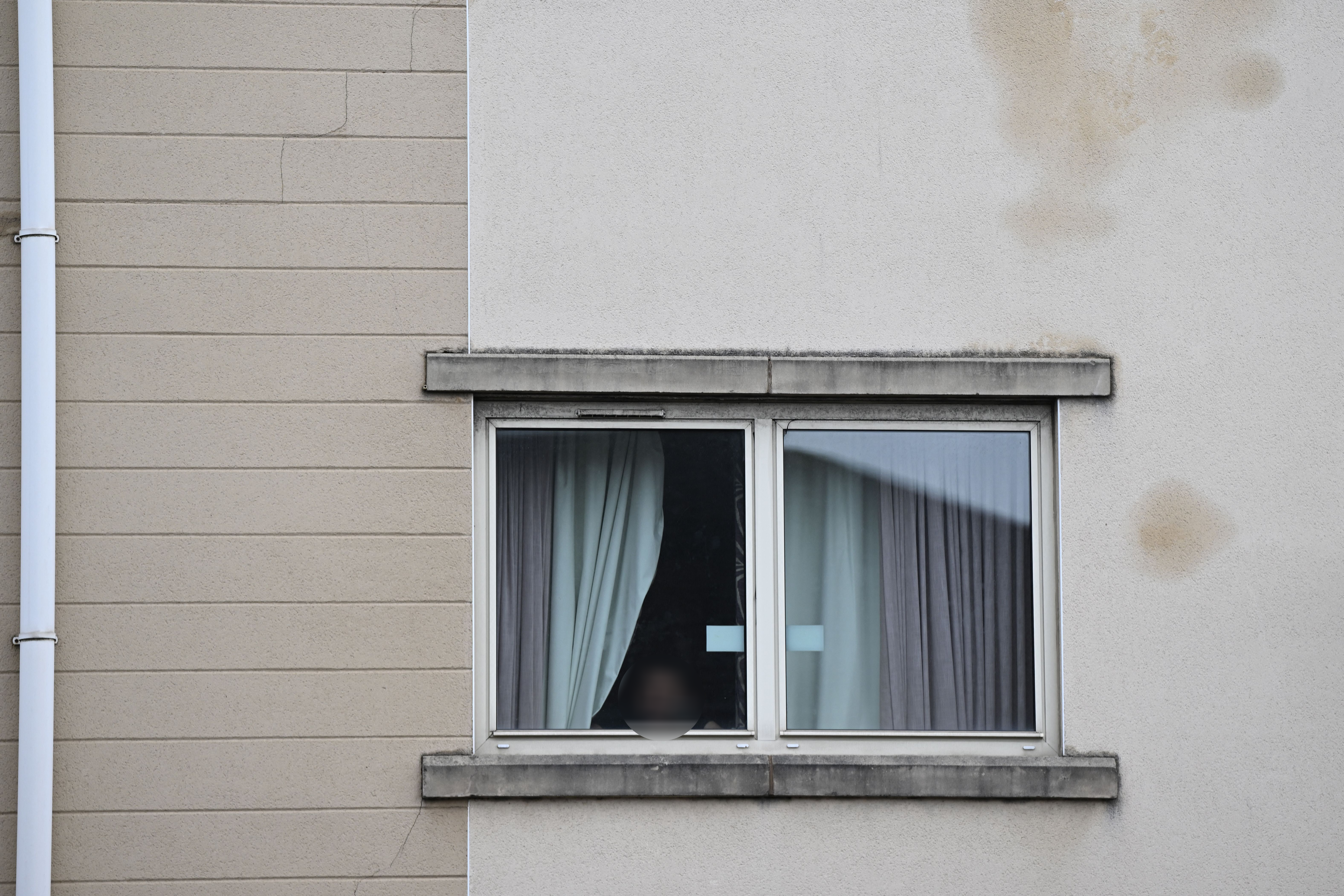 A resident can be seen at the window of a room in the Suites Hotel in Knowlsey, near Liverpool. The asylum hotel was attacked by right-wing extremist demonstrators