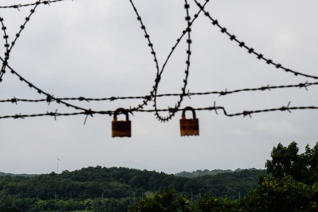 <p>Flags of South Korea (back bottom R) and North Korea (back bottom L) are seen in their respective border cities within the Demilitarised Zone (DMZ), beyond a barbed wire fence in Paju</p>