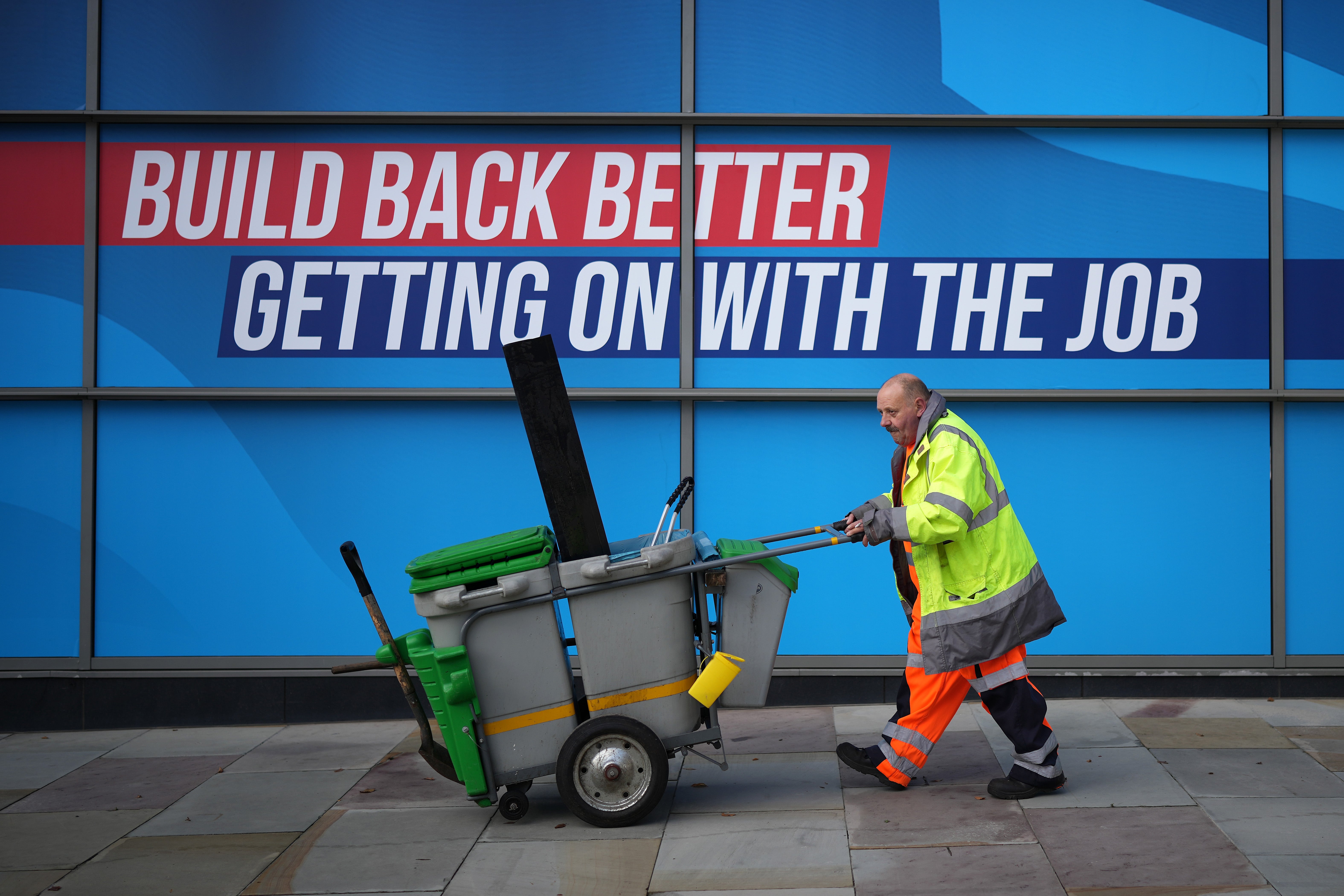 A street cleaner walks past conservative party branding