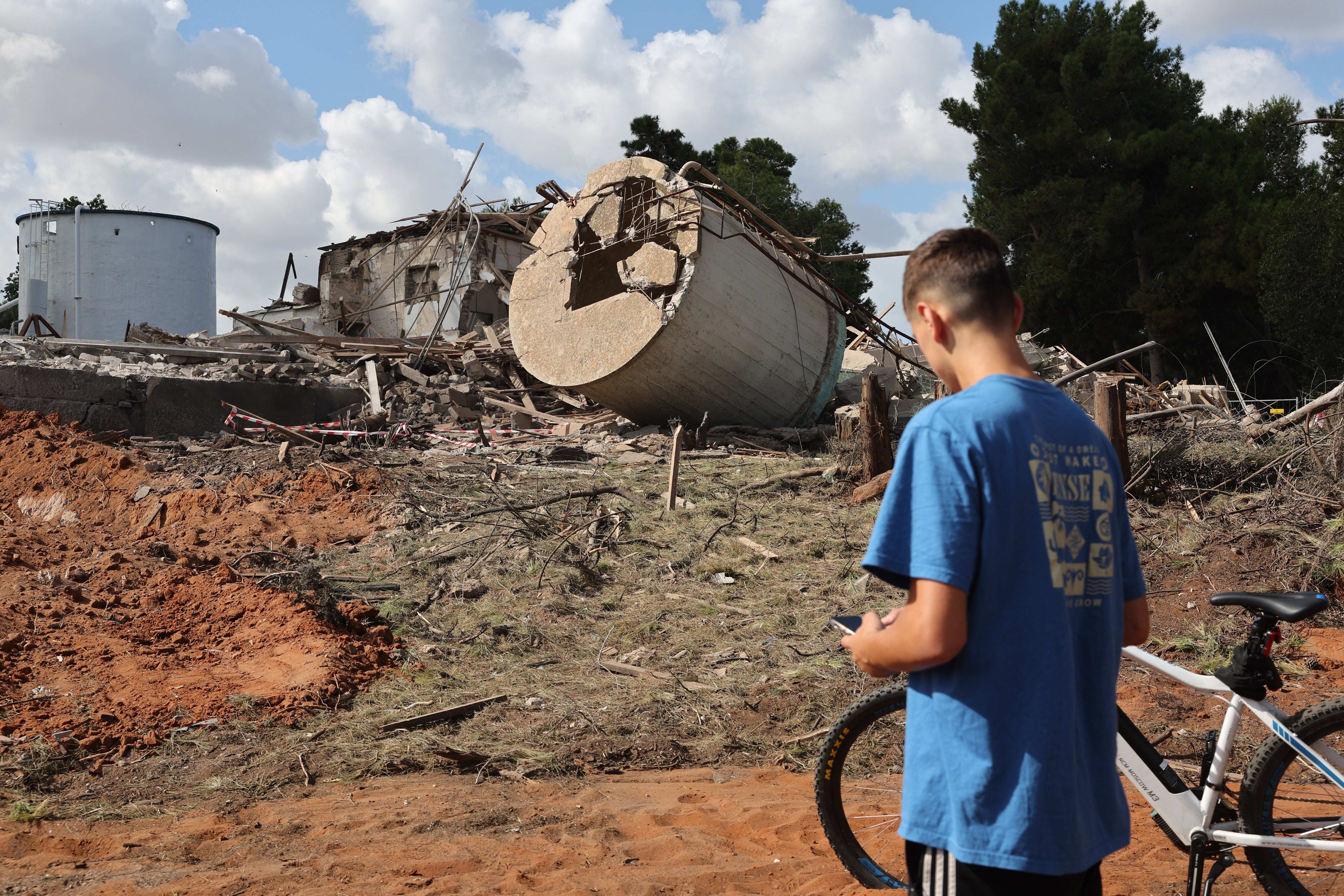 A youth in a bicycle checks the rubble of a destroyed building in Hod HaSharon in the aftermath of an Iranian missile attack on Israel