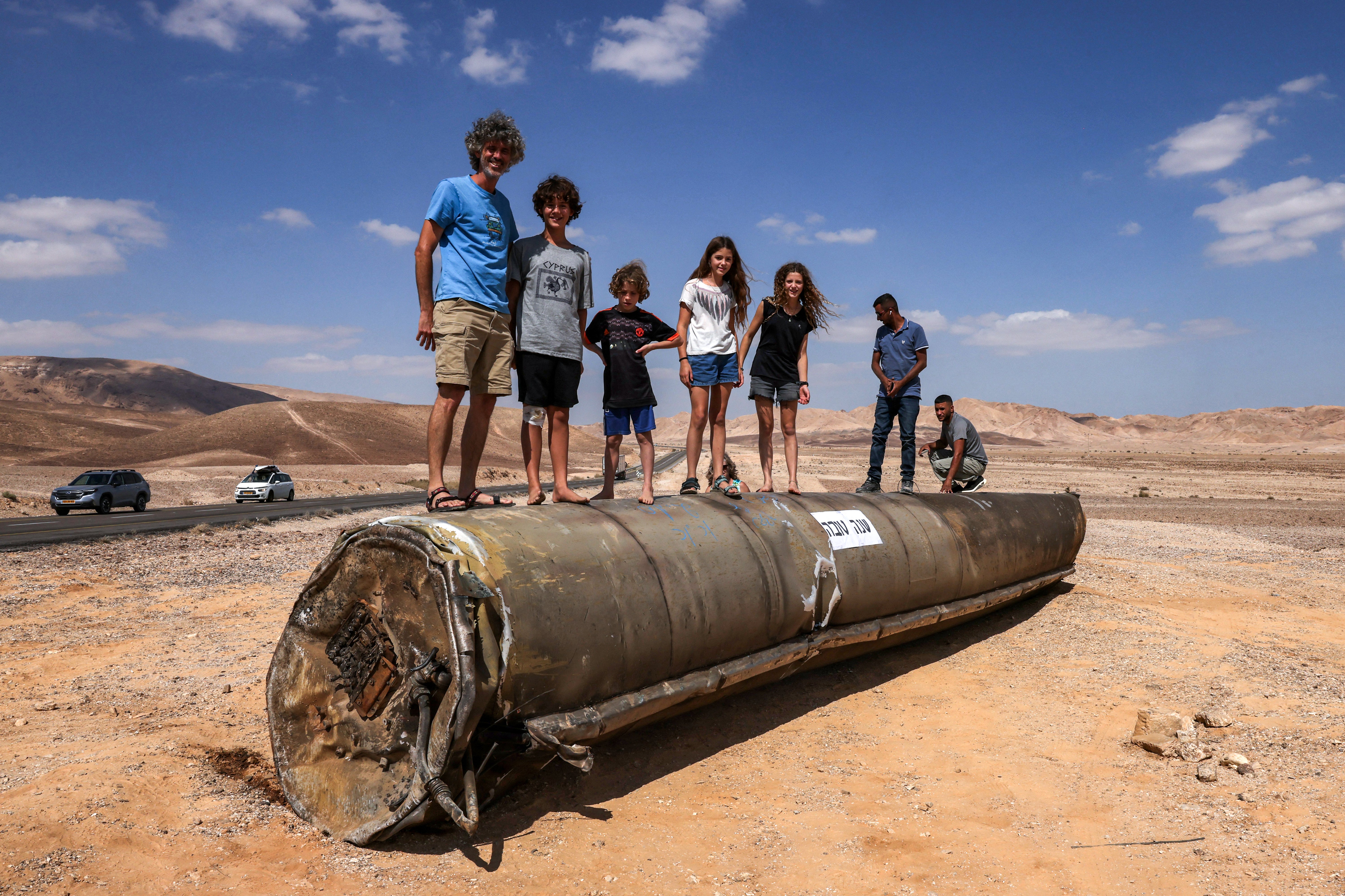 People stand on top of the remains of an Iranian missile in the Negev desert near Arad, on the border with Jordan