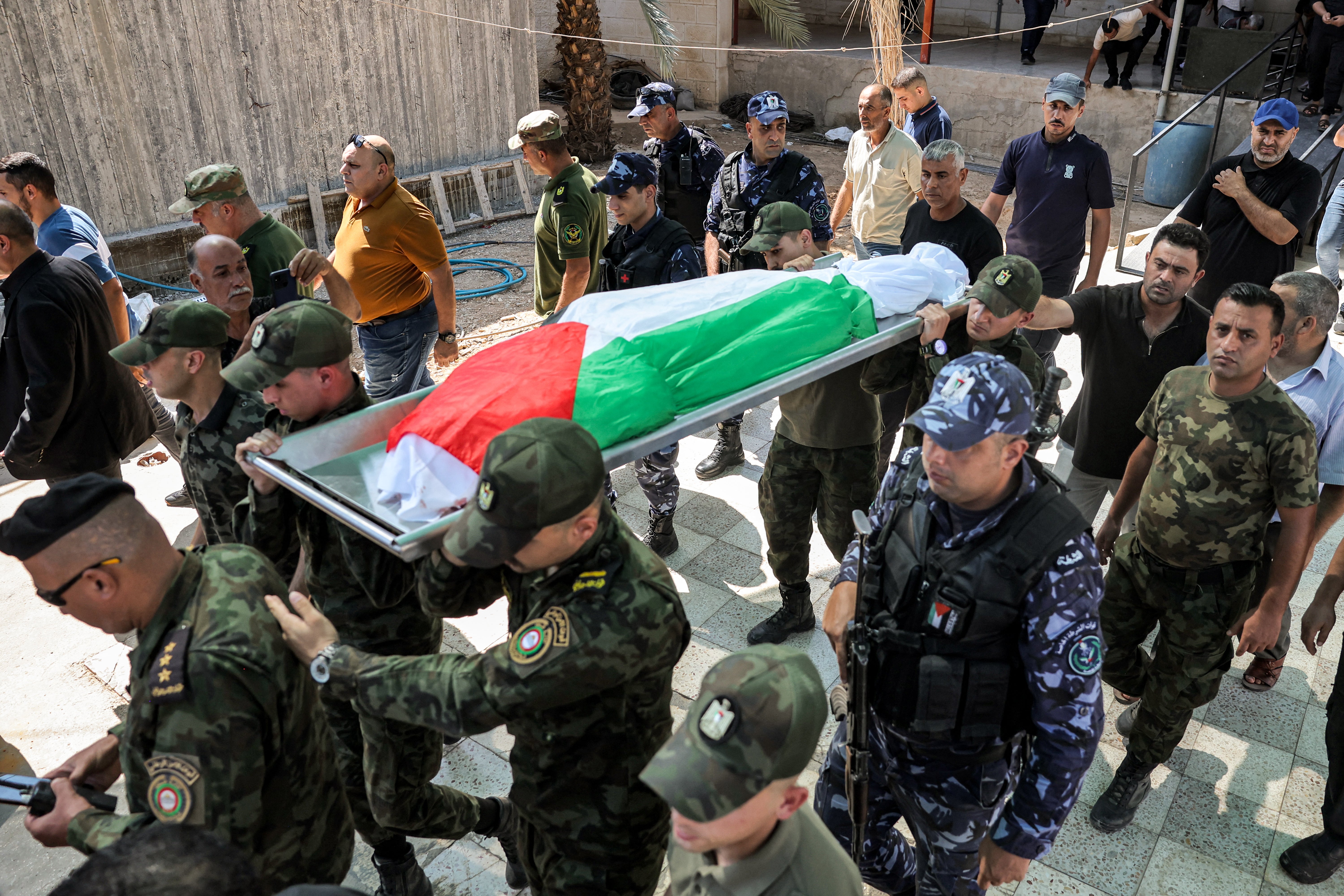 Members of the Palestinian National Security Forces carry the Palestinian-flag-draped body of Samer al-Asali, who was killed in Jericho by falling debris from one of the intercepted projectiles fired overnight by Iran on Israel, during his funeral in Jericho in the occupied West Bank