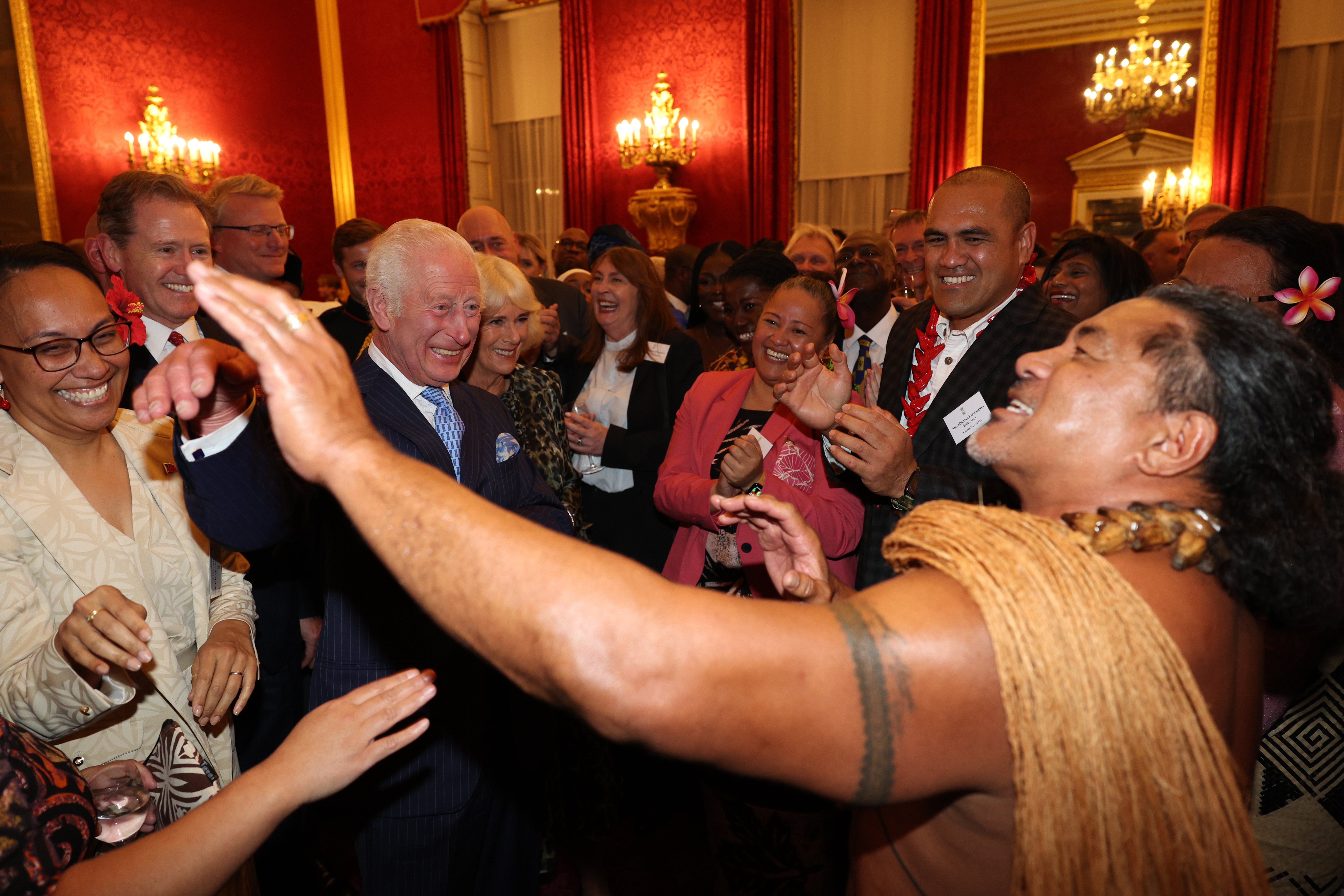 El rey Carlos III reacciona mientras el exjugador de rugby samoano Freddie Tuilagi baila durante una recepción en el Palacio de St. James en Londres.