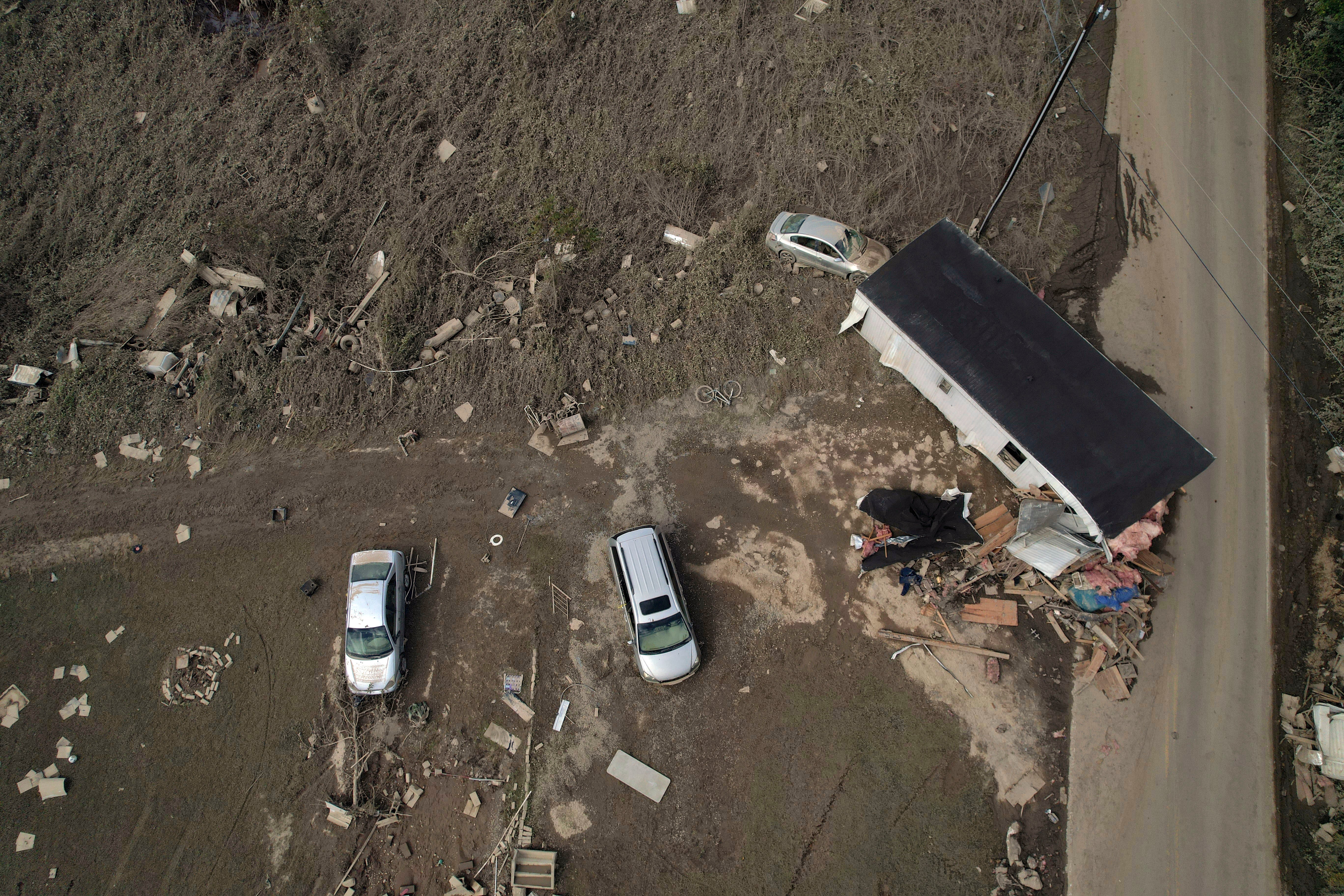 A destroyed mobile home and vehicles lay scattered across muddy land, Tuesday, Oct. 1, 2024, in Hendersonville, N.C.,