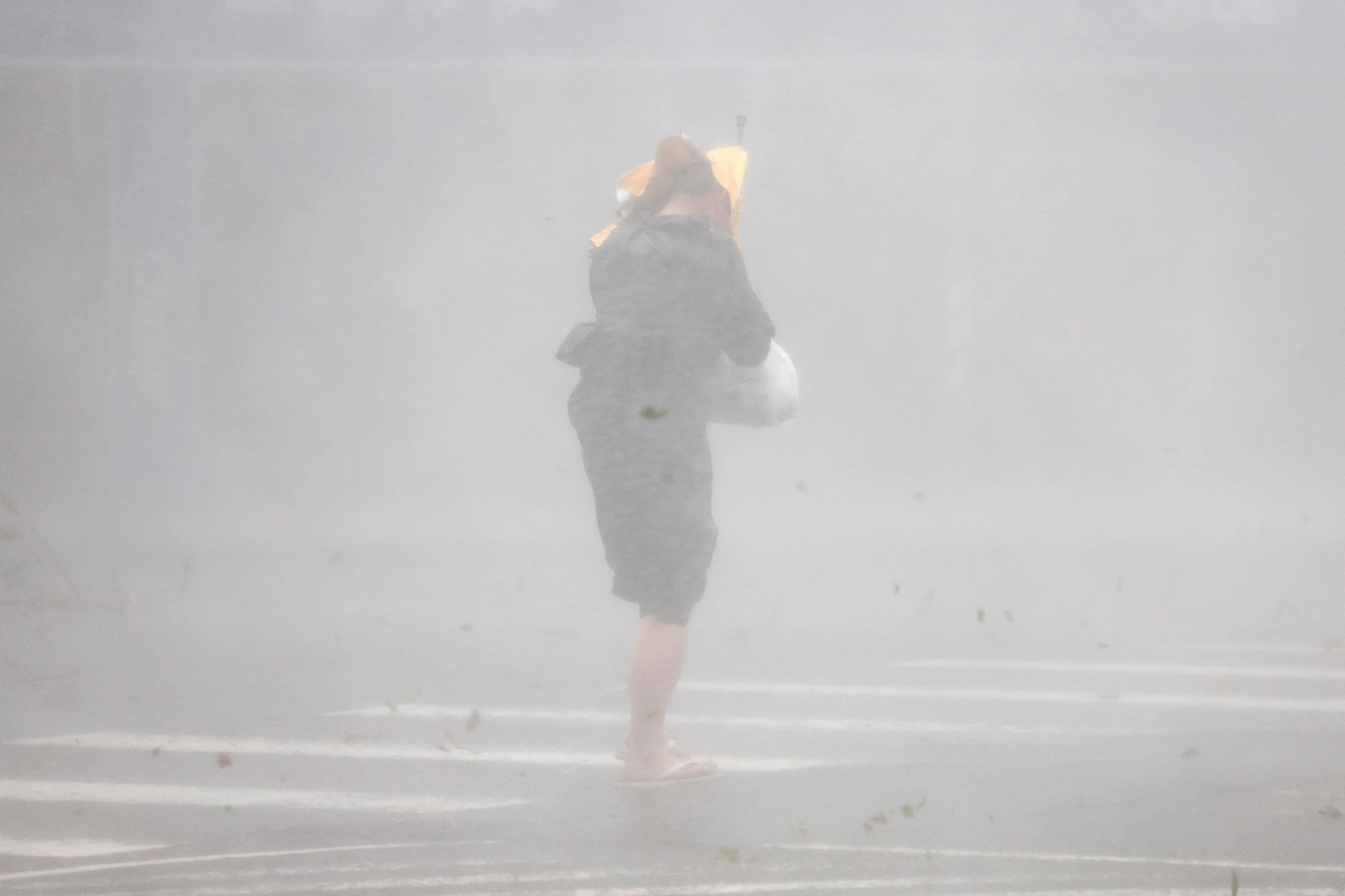 A person crosses the street through strong winds and heavy rain brought on by Typhoon Krathon in Kaohsiung city, Taiwan