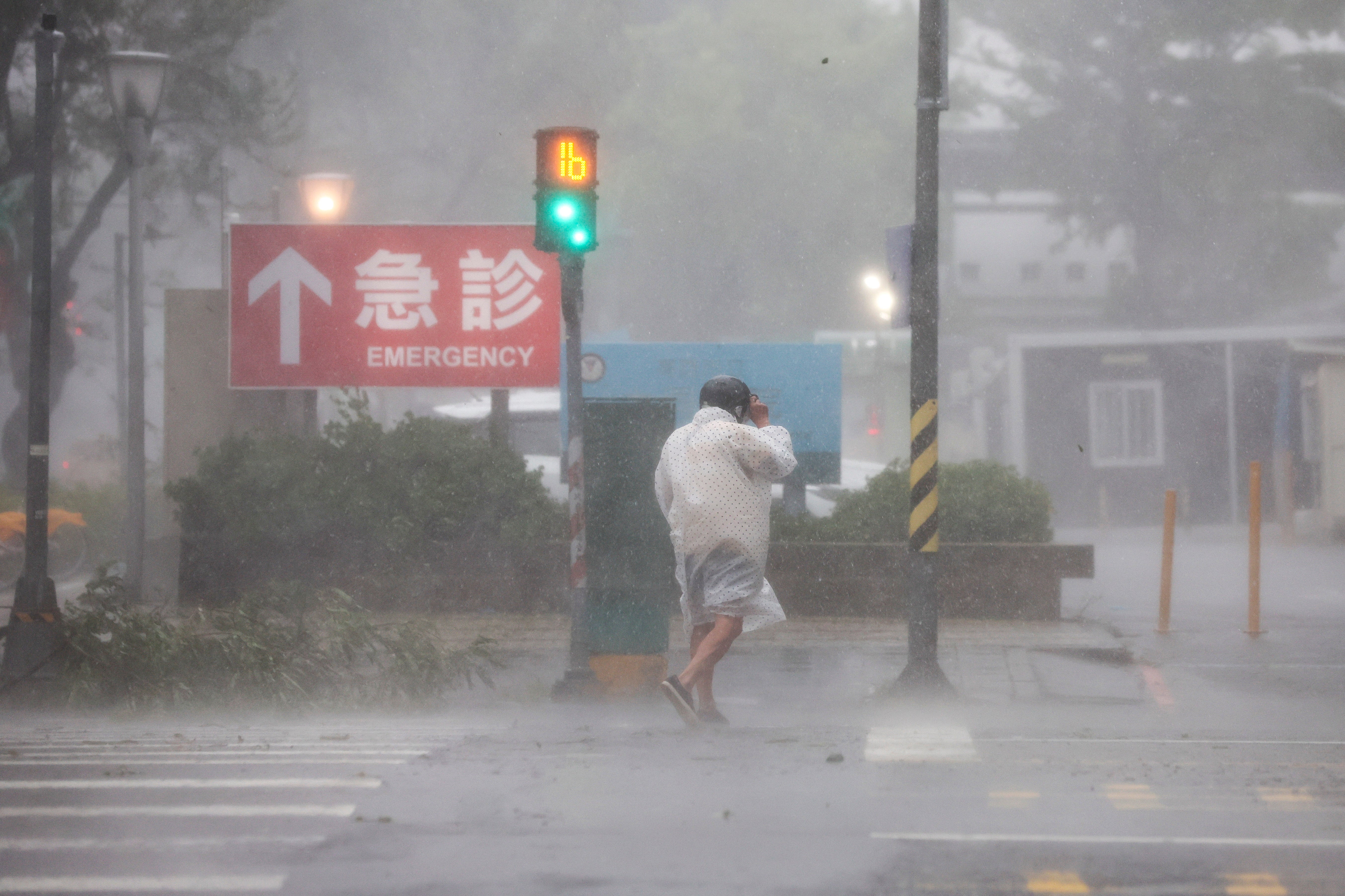 A person crosses the street through strong winds and heavy rain brought on by Typhoon Krathon in Kaohsiung city, Taiwan