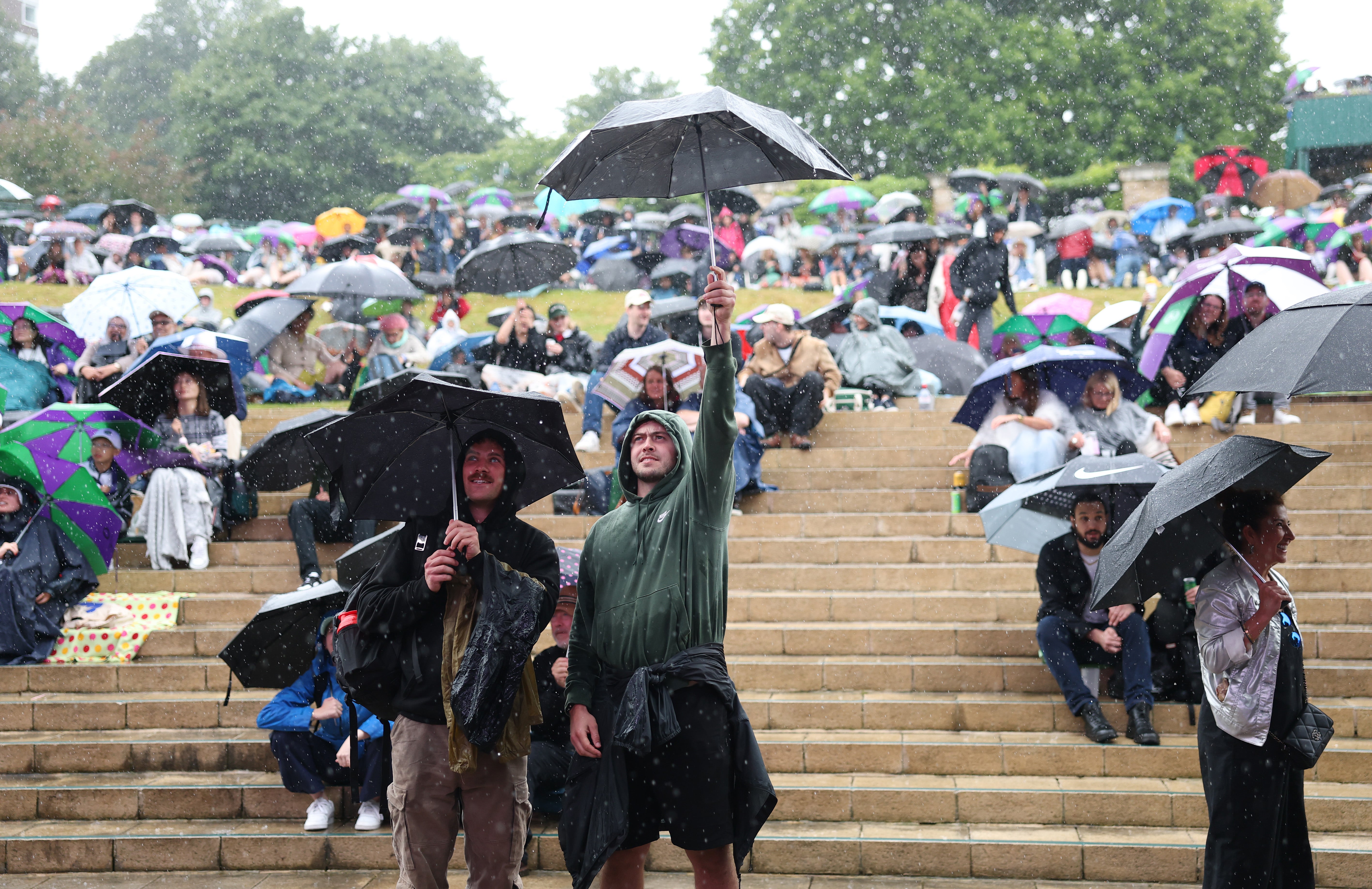 Spectators tackle rain during Wimbledon day nine, July 2024