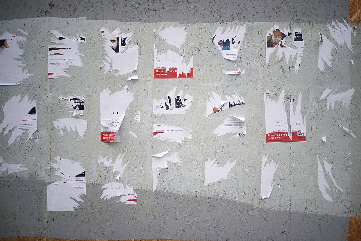 A row of ripped posters which displayed the names and faces of some of the hostages taken by Hamas