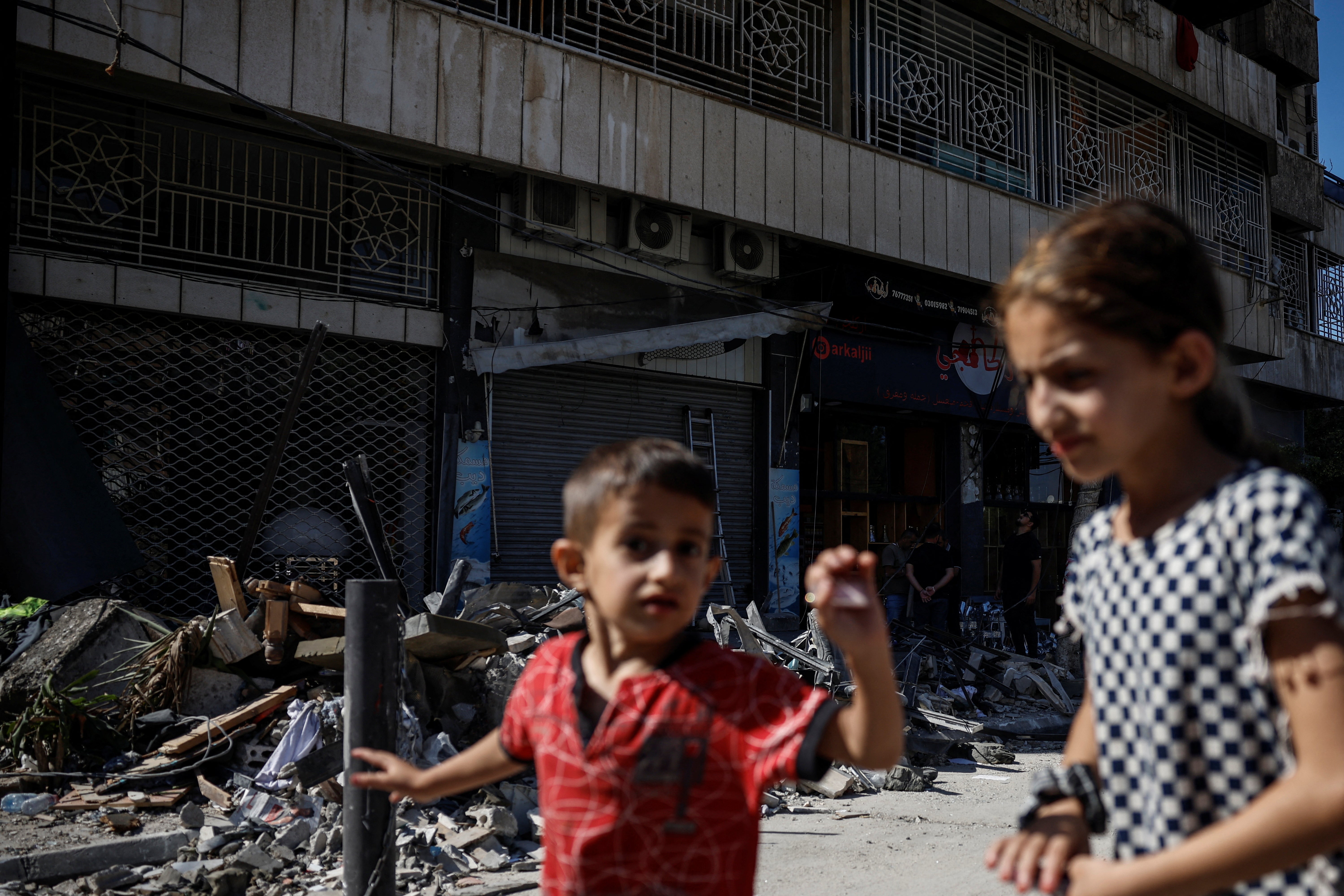 Children walk past a damaged building at the site of an Israeli strike on central Beirut’s Bachoura neighbourhood