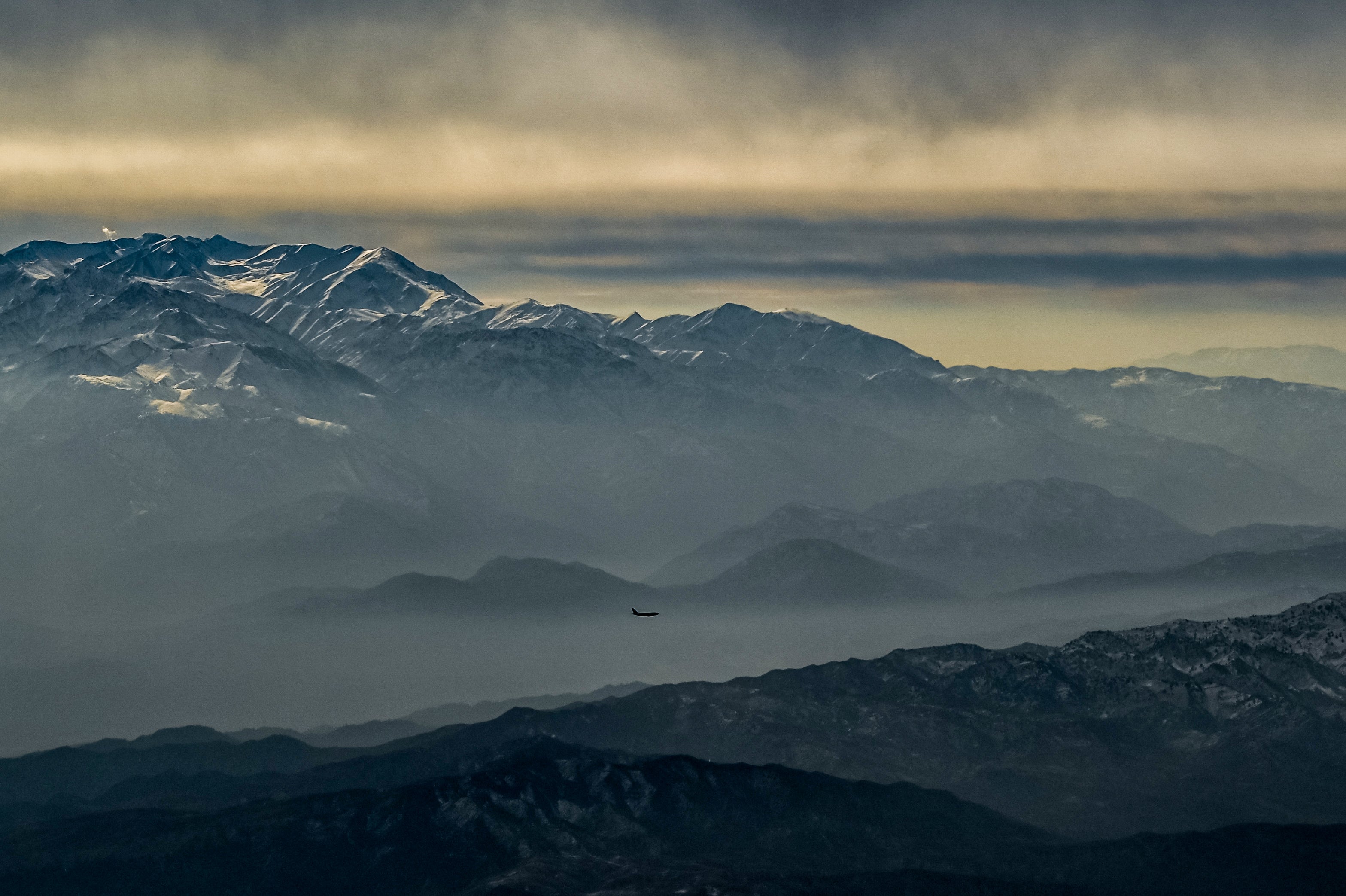 This picture taken from a passenger plane shows an airplane flying past a snow-covered mountain range near Kabul