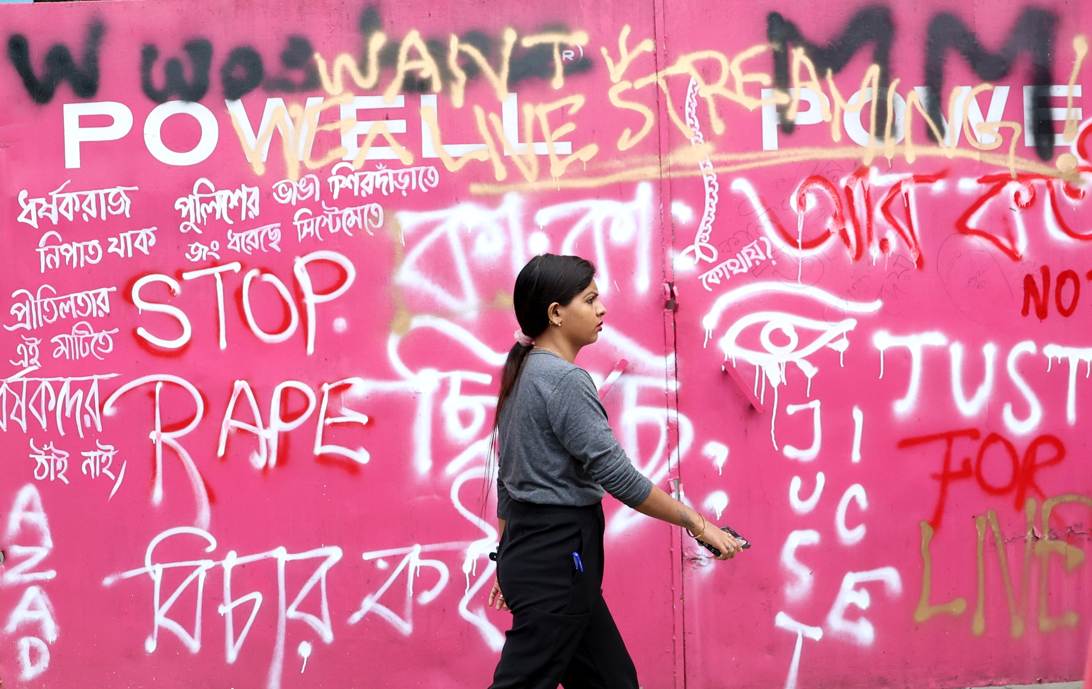 Junior doctor walks past a painted wall during a protest against rape and murder of medico in Kolkata