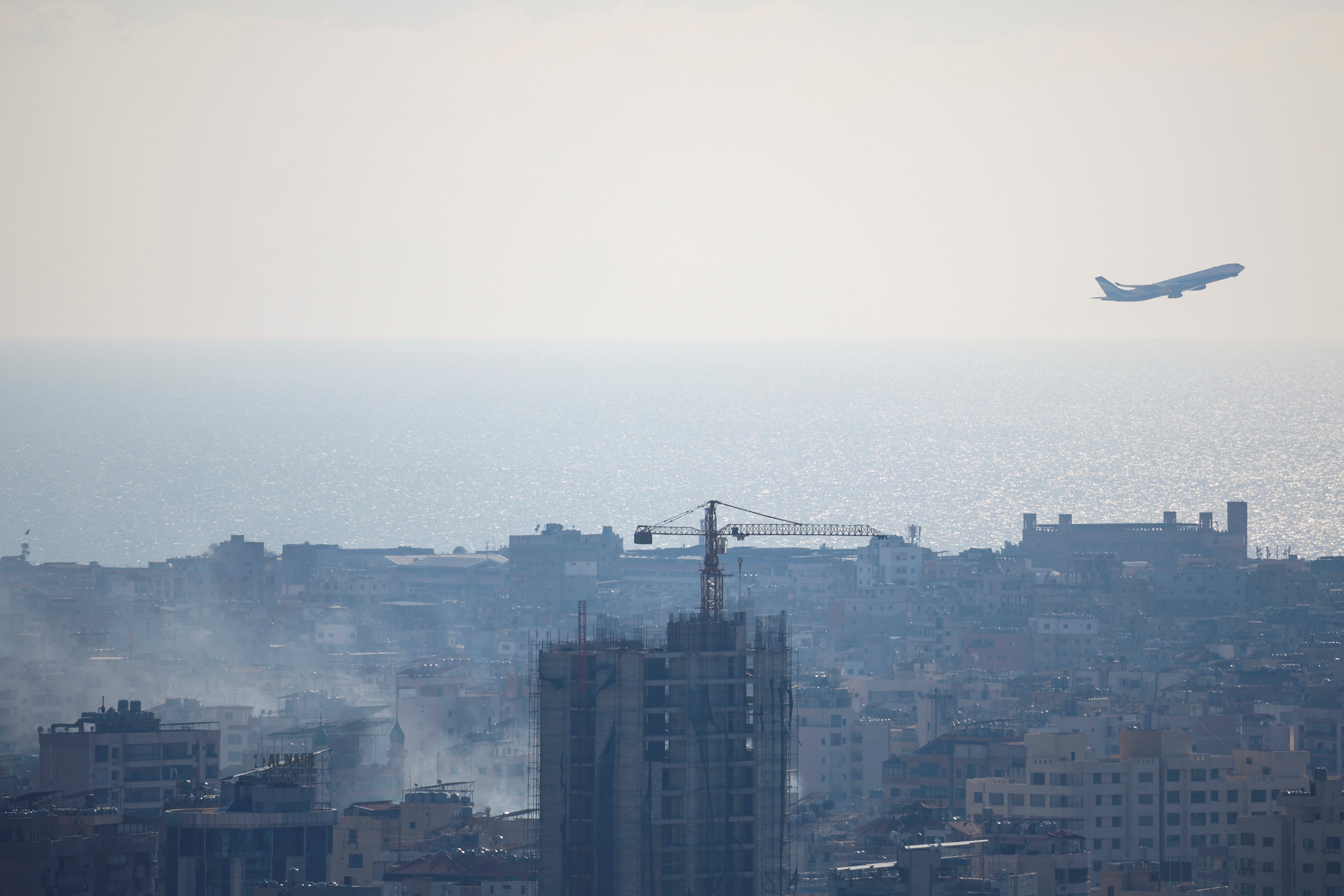 A plane takes off as smoke from an Israeli strike billows near Beirut’s Rafic Hariri International Airport in Beirut, Lebanon