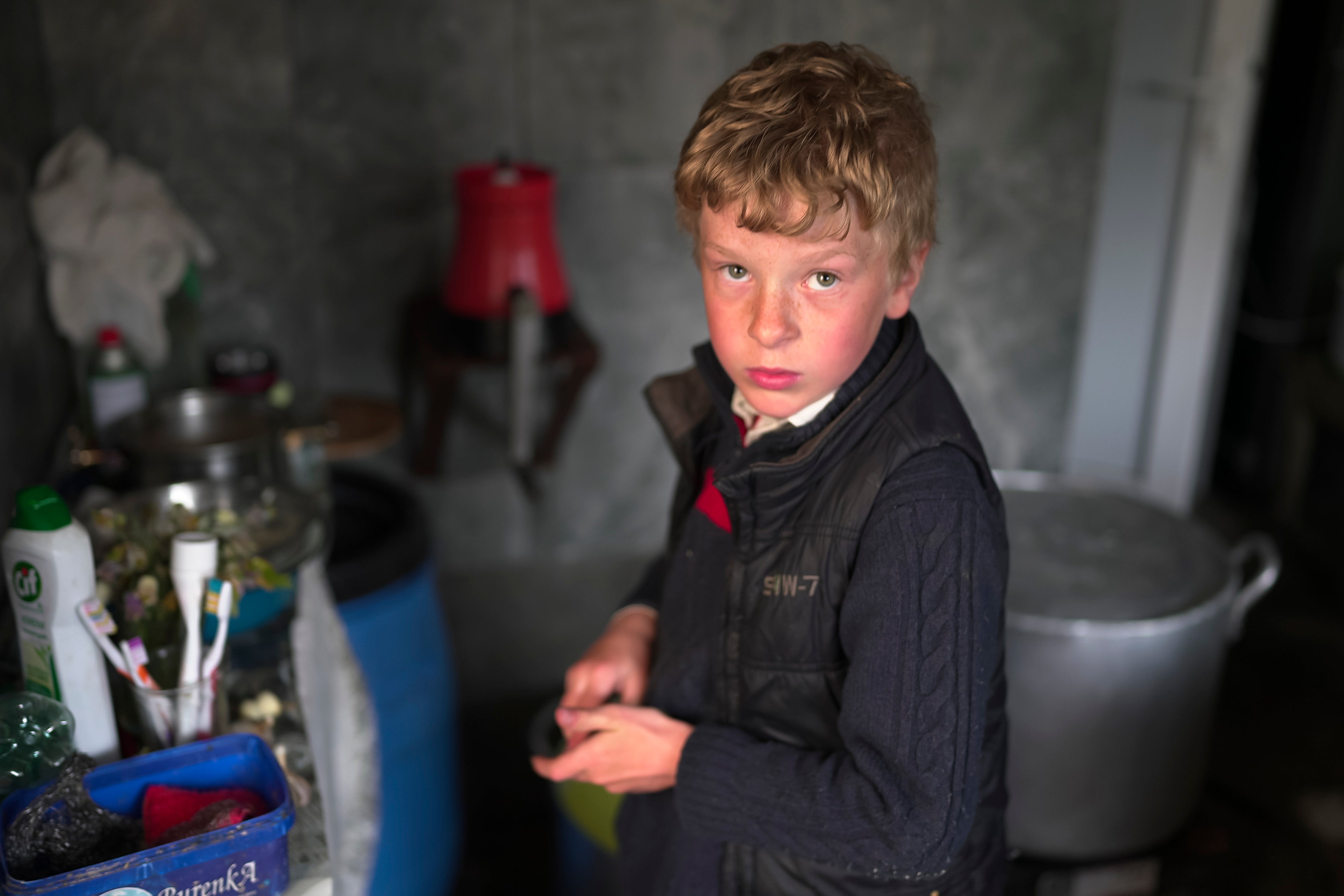 Ilya Strukov, 10, looks on in the kitchen as his family cooks dinner in their house in the remote mountain village