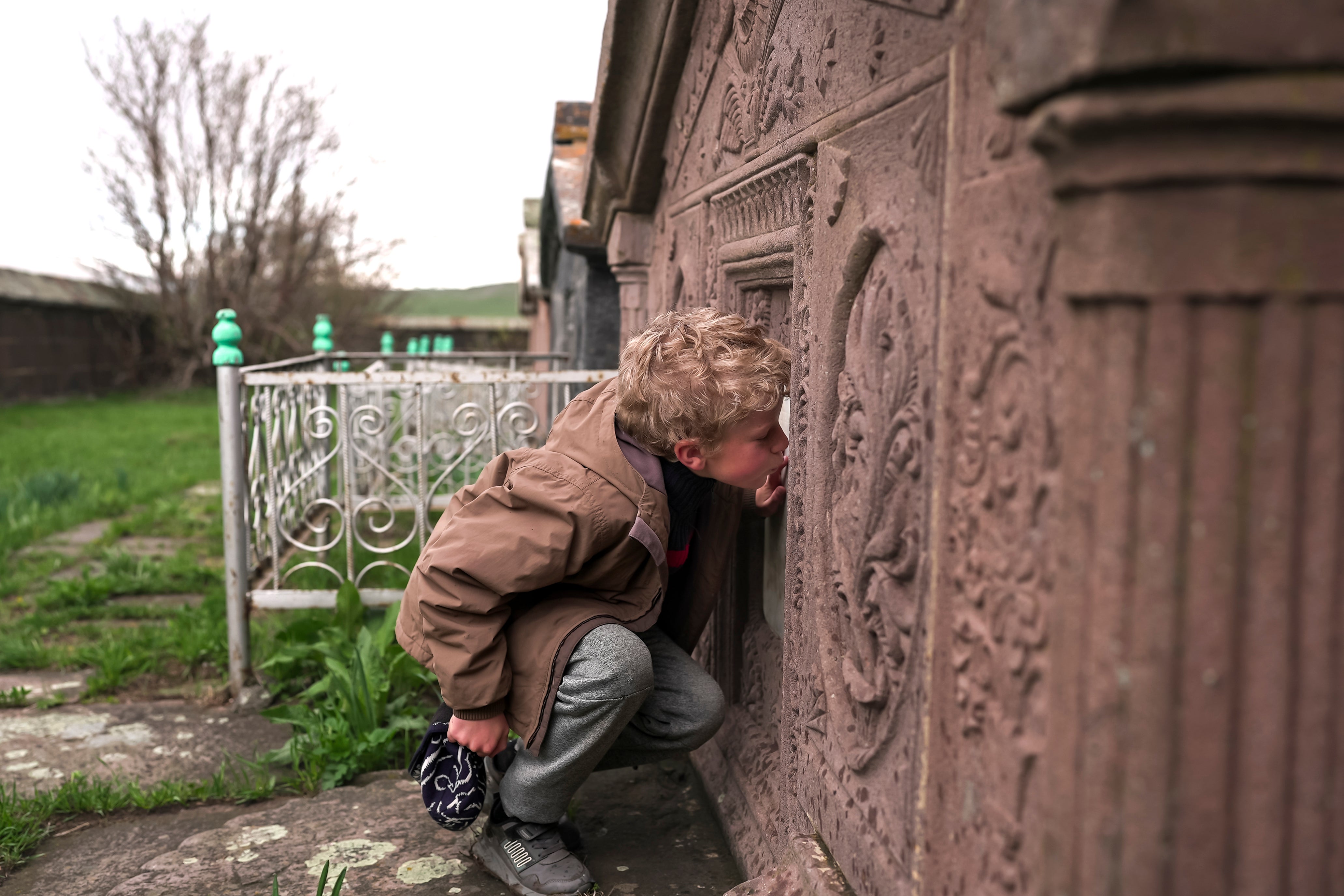 Ilya Strukov, 10, kisses a tombstone on a grave of his Doukhobor ancestors at a cemetery outside of the remote mountain village