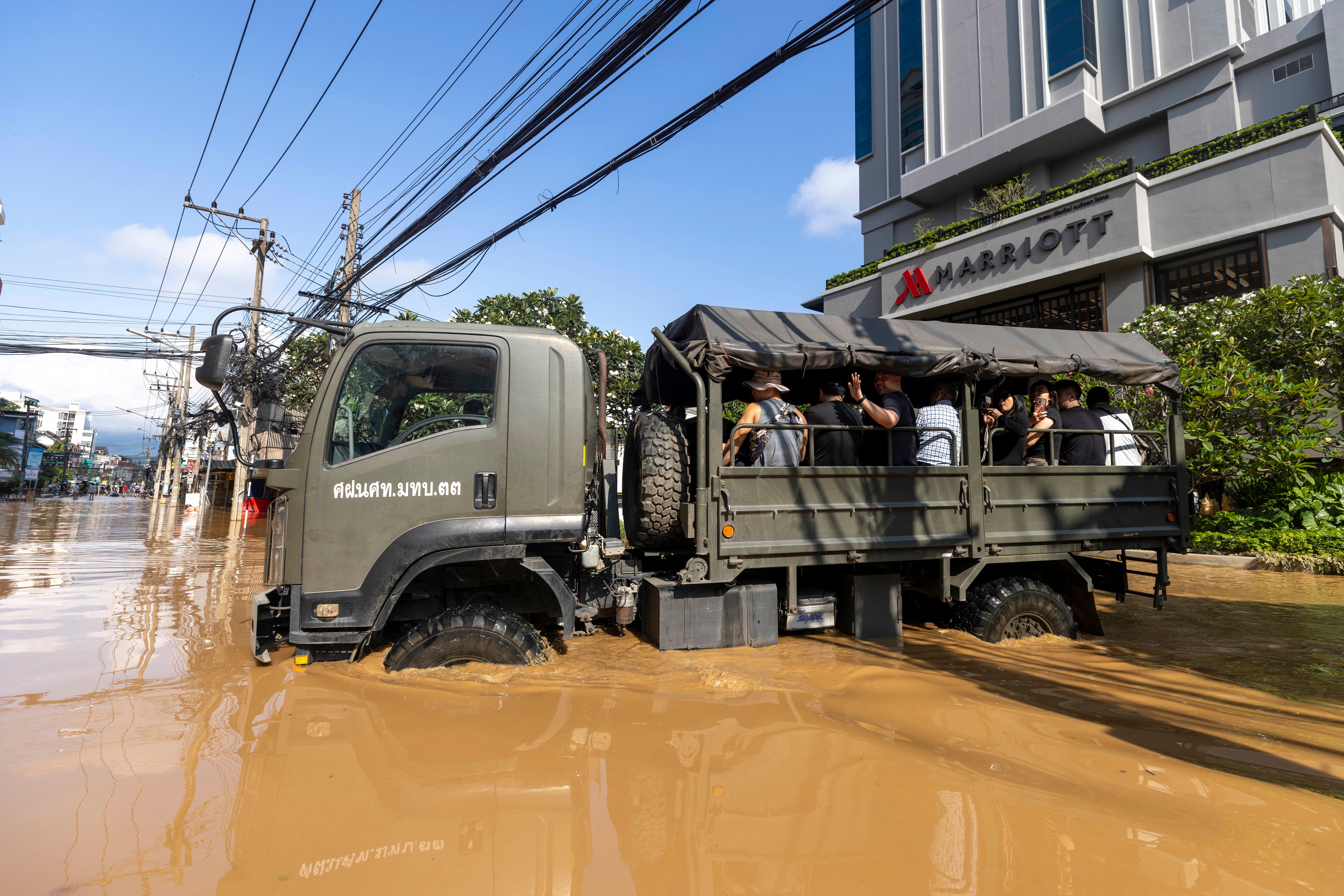 Inundações na TailândiaTuristas evacuam de uma área atingida por enchentes na província de Chiang Mai, Tailândia, domingo