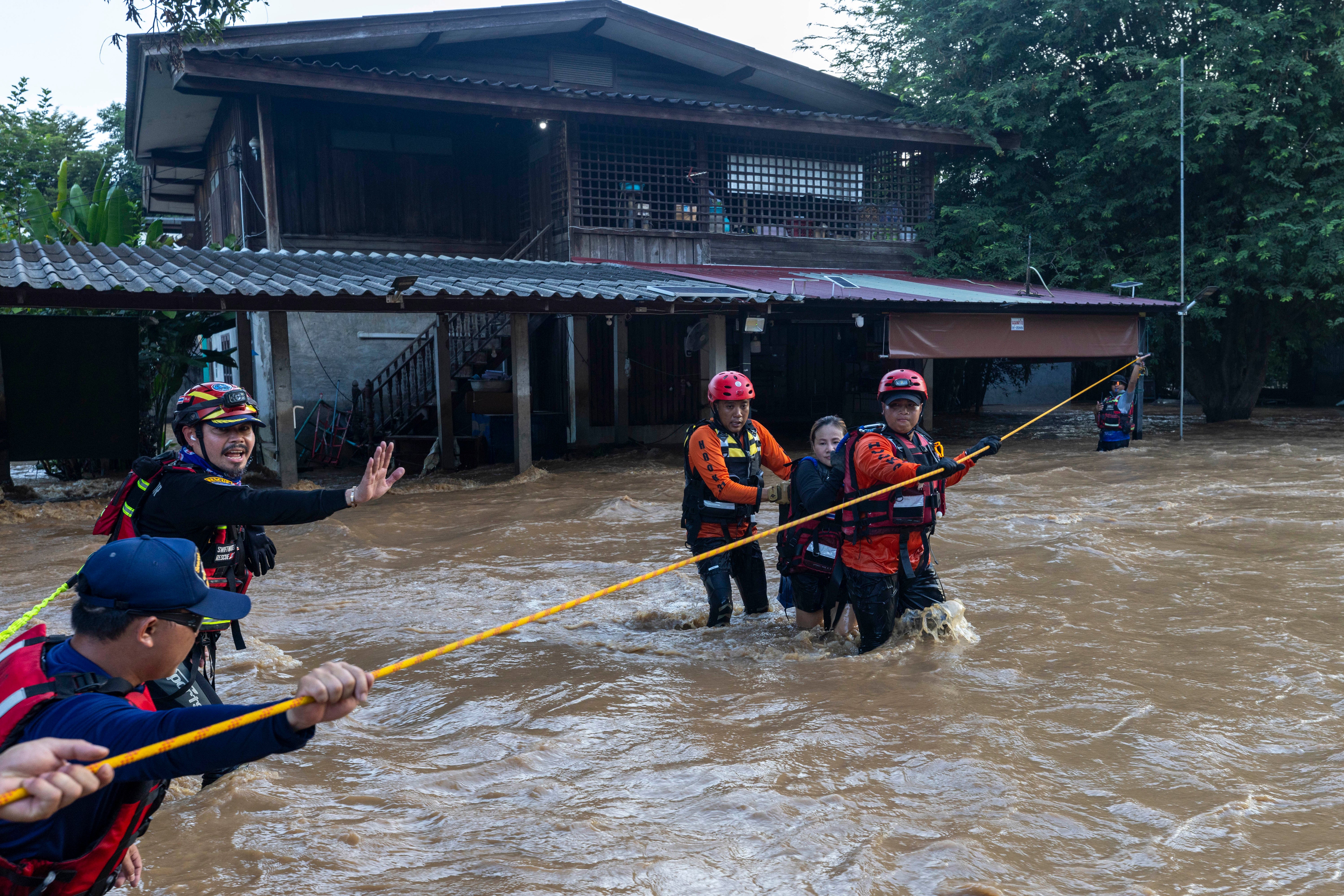 Equipes de resgate tailandesas ajudam uma mulher em uma área atingida por enchentes na província de Chiang Mai, Tailândia