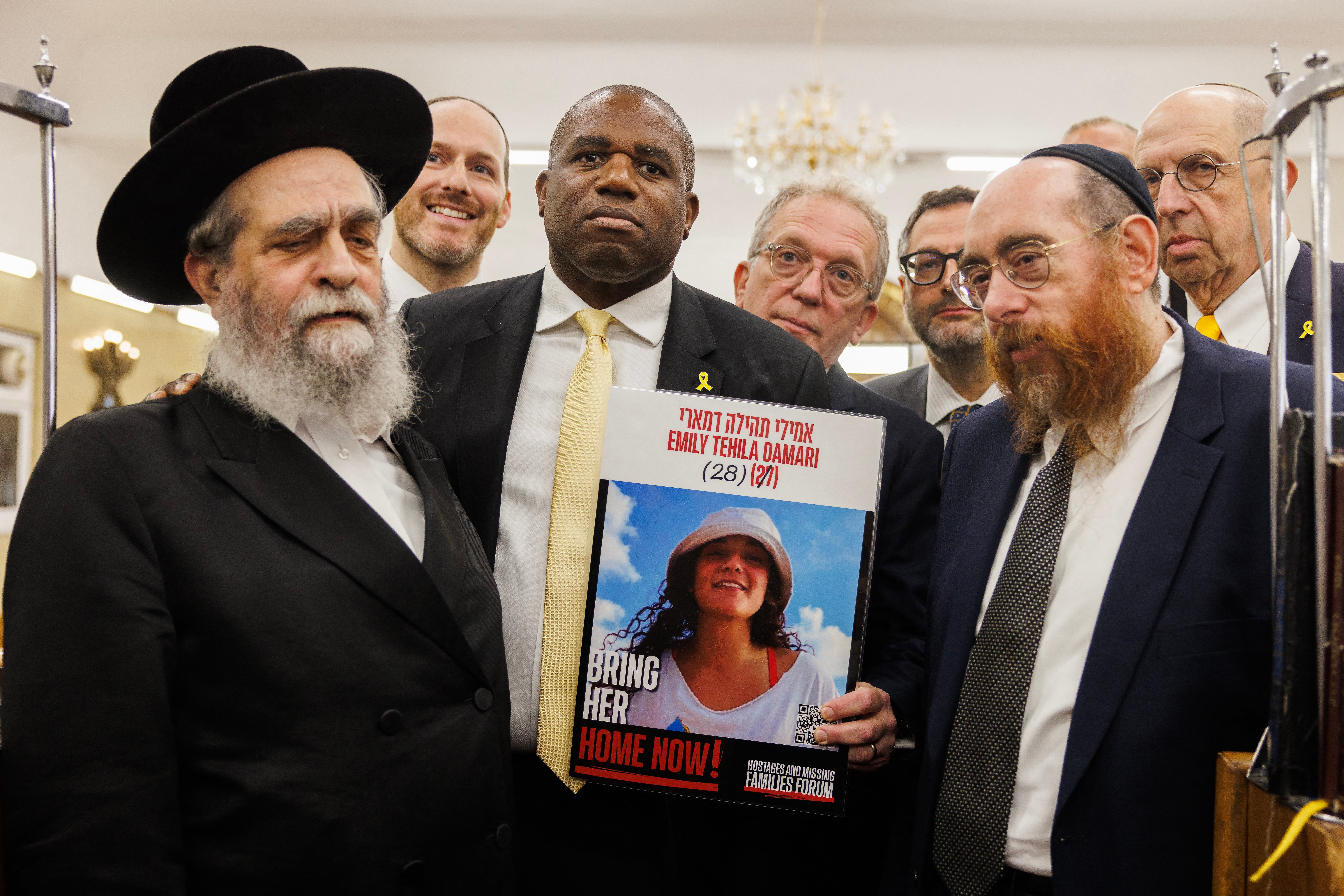 Foreign secretary David Lammy holds a placard showing hostage Emily Tehila Damari while posing for a photo with members of the Jewish community during a visit to South Tottenham United Synagogue, London